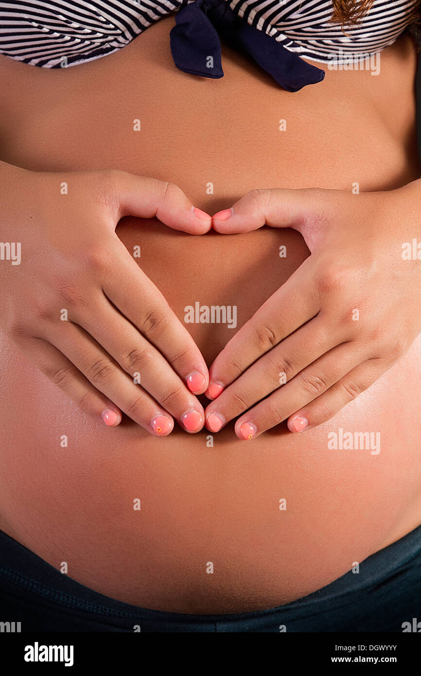 Vue d'un ventre de femme enceinte avec mains formant un cœur. Banque D'Images