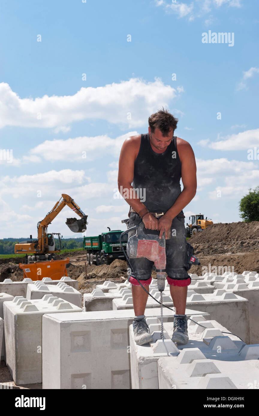 Le forage de trous dans la pierre travailleur de blocs qui sont à utiliser à l'emplacement de l'édifice l'essai de charge sur un site de construction dans la région de Fridolfing Banque D'Images