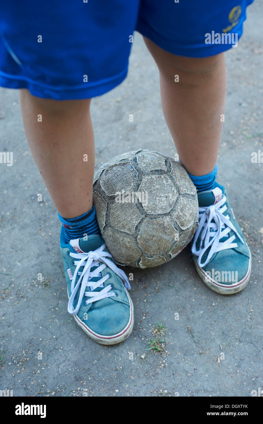 Vue détaillée d'enfants jambes avec un vieux foot Banque D'Images