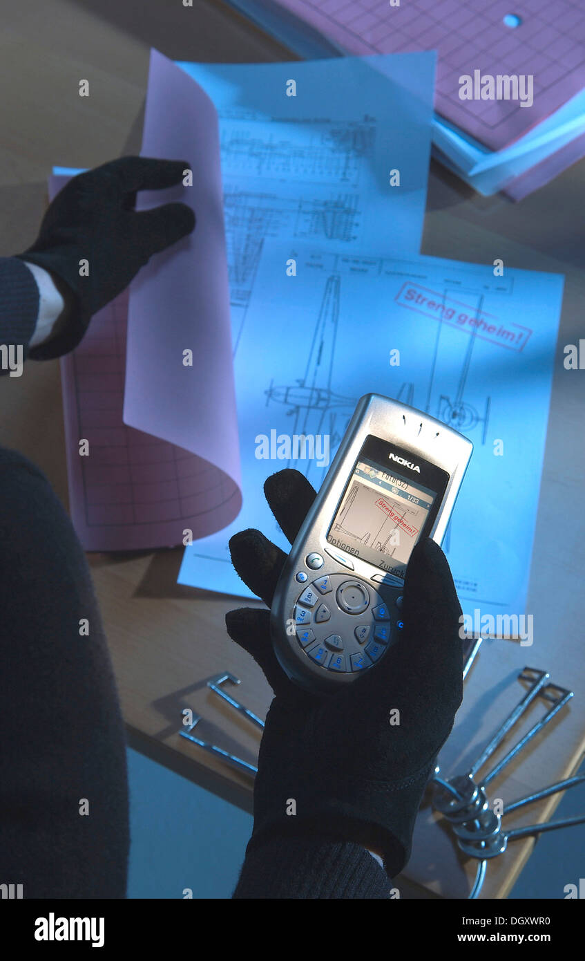 À l'aide d'un antivol téléphone appareil photo pour prendre une photo de plans secrets, image symbolique pour l'espionnage industriel Banque D'Images