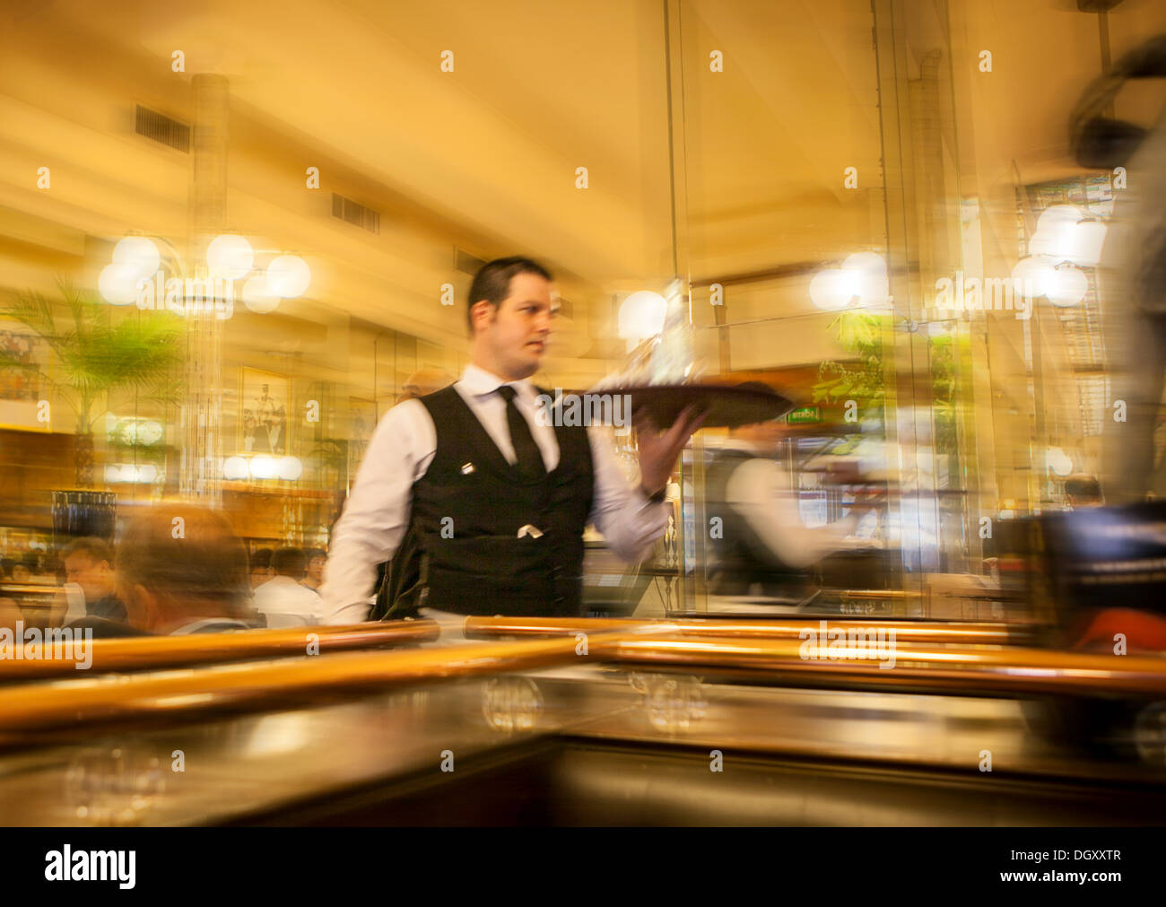 Serveur français tenant un plateau à la hâte d'un bar restaurant à Paris Banque D'Images