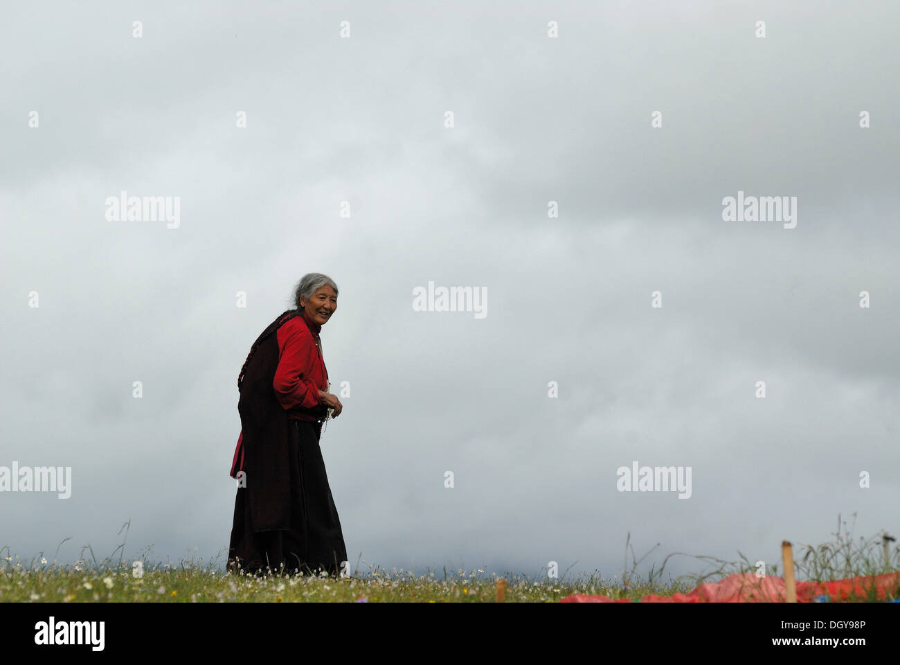 Personnes âgées femme tibétaine portant un costume traditionnel tibétain, marcher sur un pèlerinage de Kora dans les prairies d'Tagong près du Banque D'Images