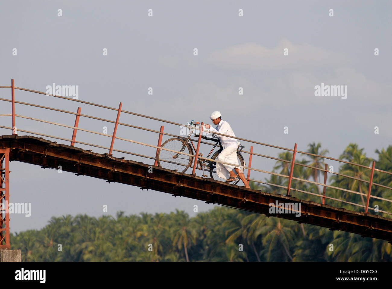 Homme marchant son vélo sur un pont à travers les Backwaters, Nileshwaram, côte de Malabar, dans le nord de Kerala, Kerala, Inde du sud Banque D'Images