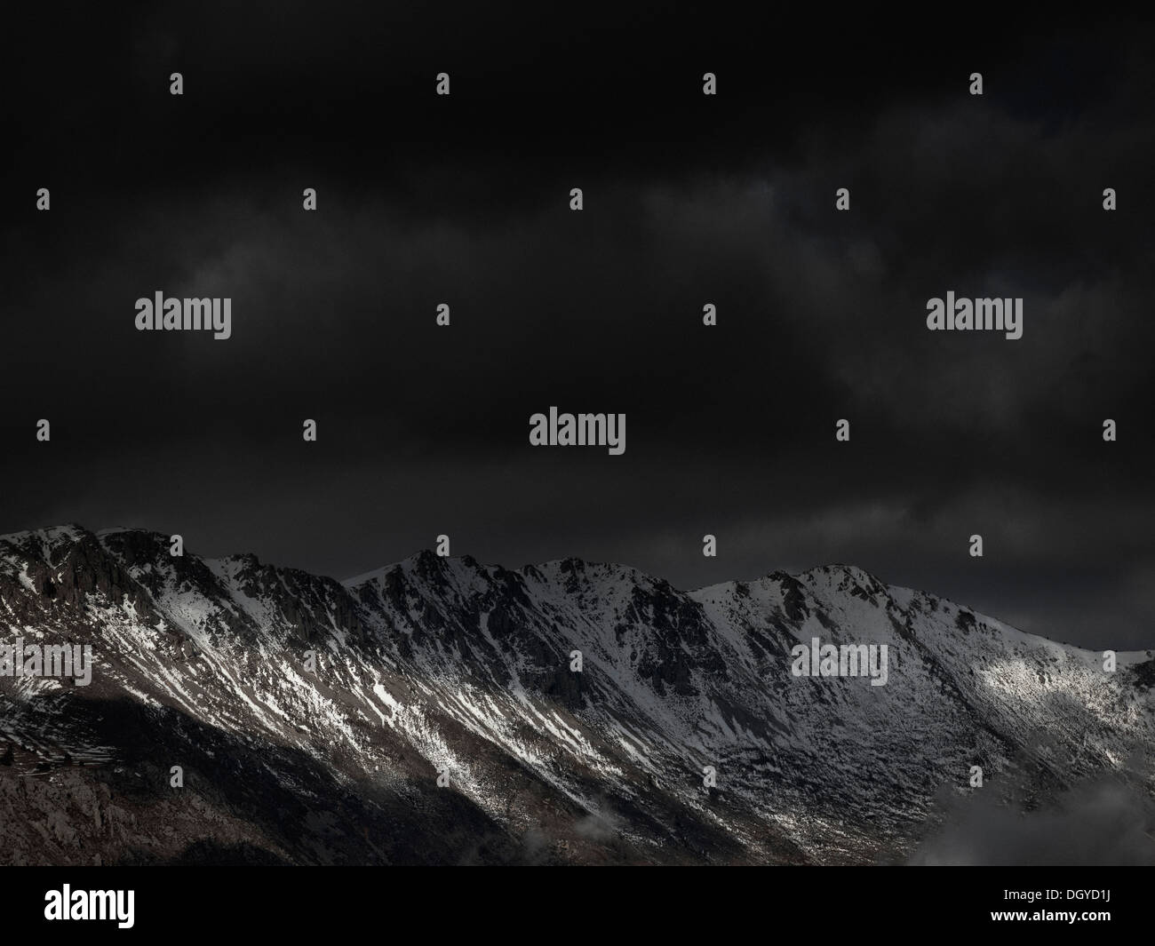 Un ciel menaçant avec quelques rayons du soleil percent sur une chaîne de montagnes Banque D'Images