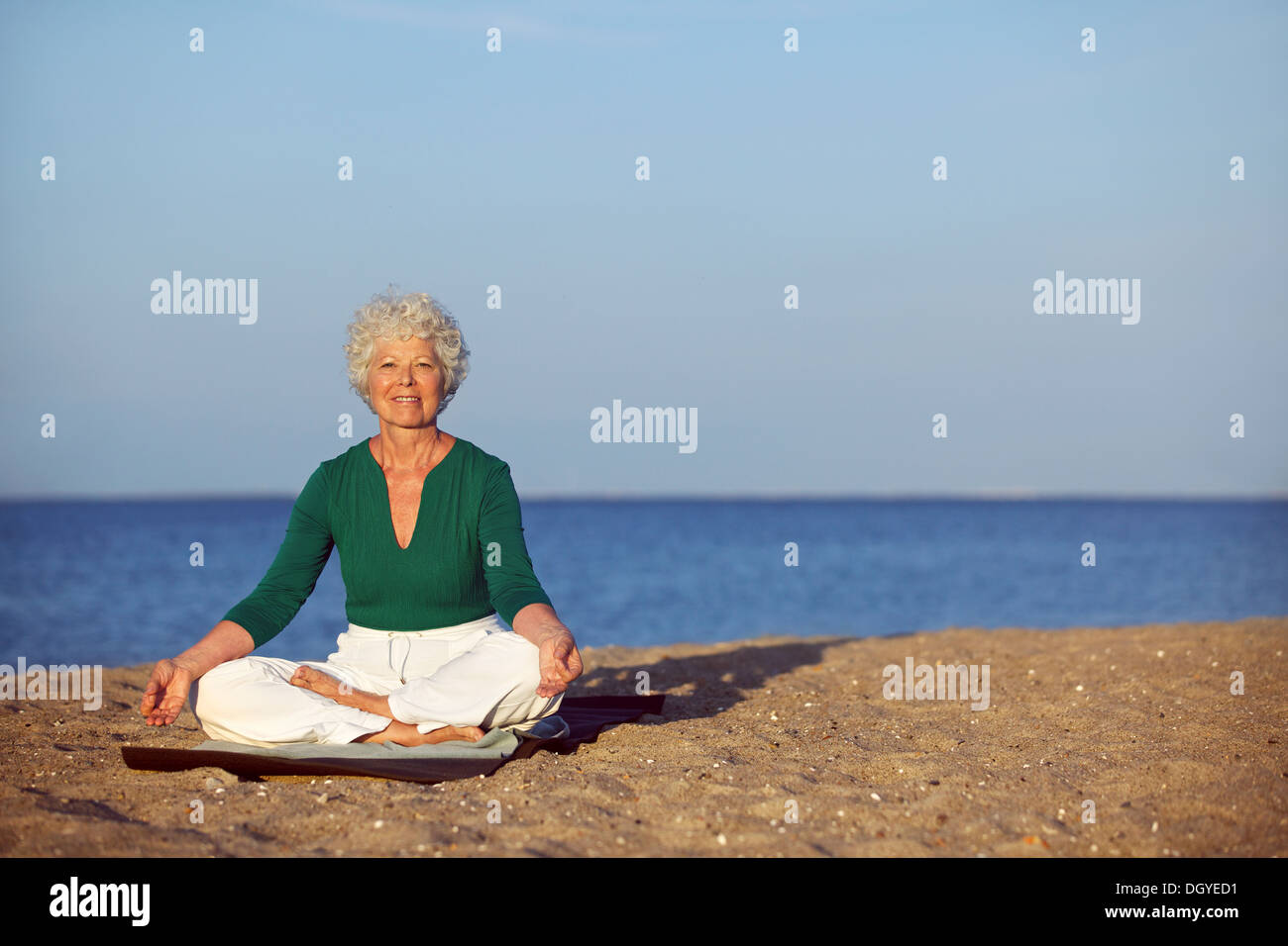 Portrait de la femme senior méditant sur le bord de la mer avec beaucoup de copyspace. Femme aîné faisant exercice de relaxation Banque D'Images