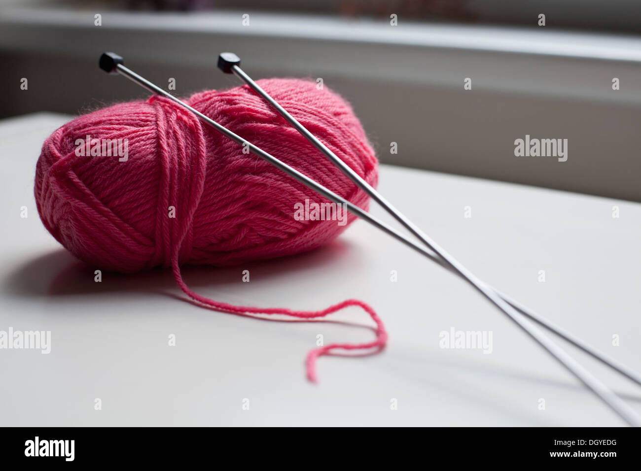 Une pelote de laine avec une paire d'aiguilles à tricoter pour se pencher sur elle Banque D'Images