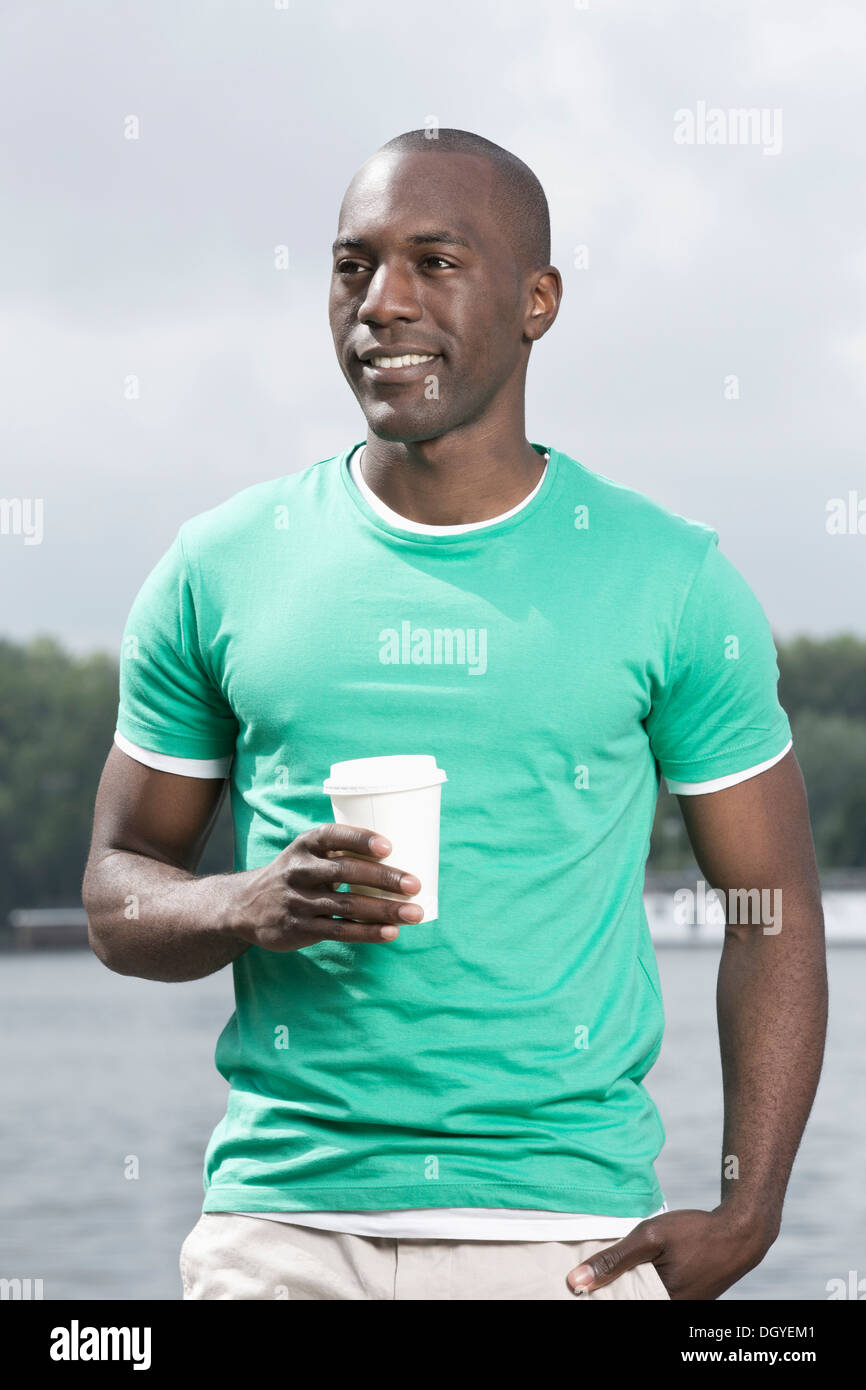 L'homme de vous détendre avec une tasse à café jetable by lake Banque D'Images L'homme de vous détendre avec une tasse à café jetable by lake Banque D'Images
