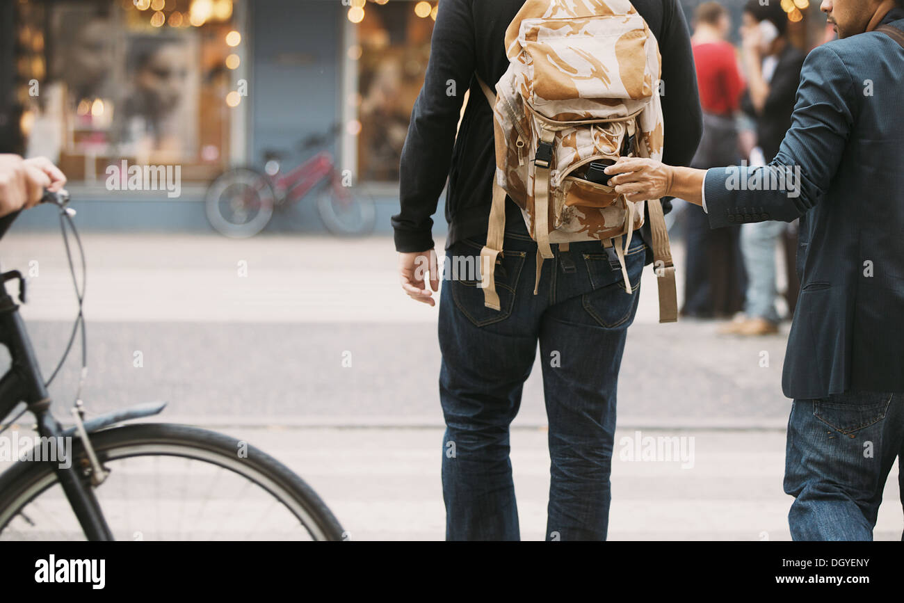 Voleur voler wallet de sac à dos d'un homme marchant sur la rue pendant la journée. La tire dans la rue pendant la journée Banque D'Images