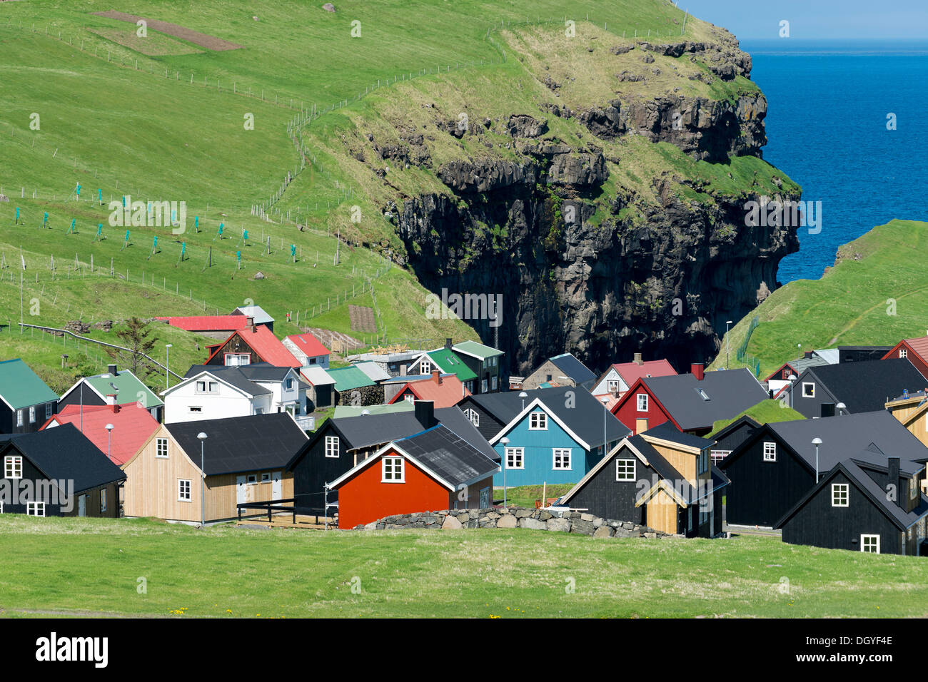 Village typique avec ses maisons colorées, des falaises à l'arrière, mais confortables et disposent, Eysturoy, îles Féroé, Danemark Banque D'Images