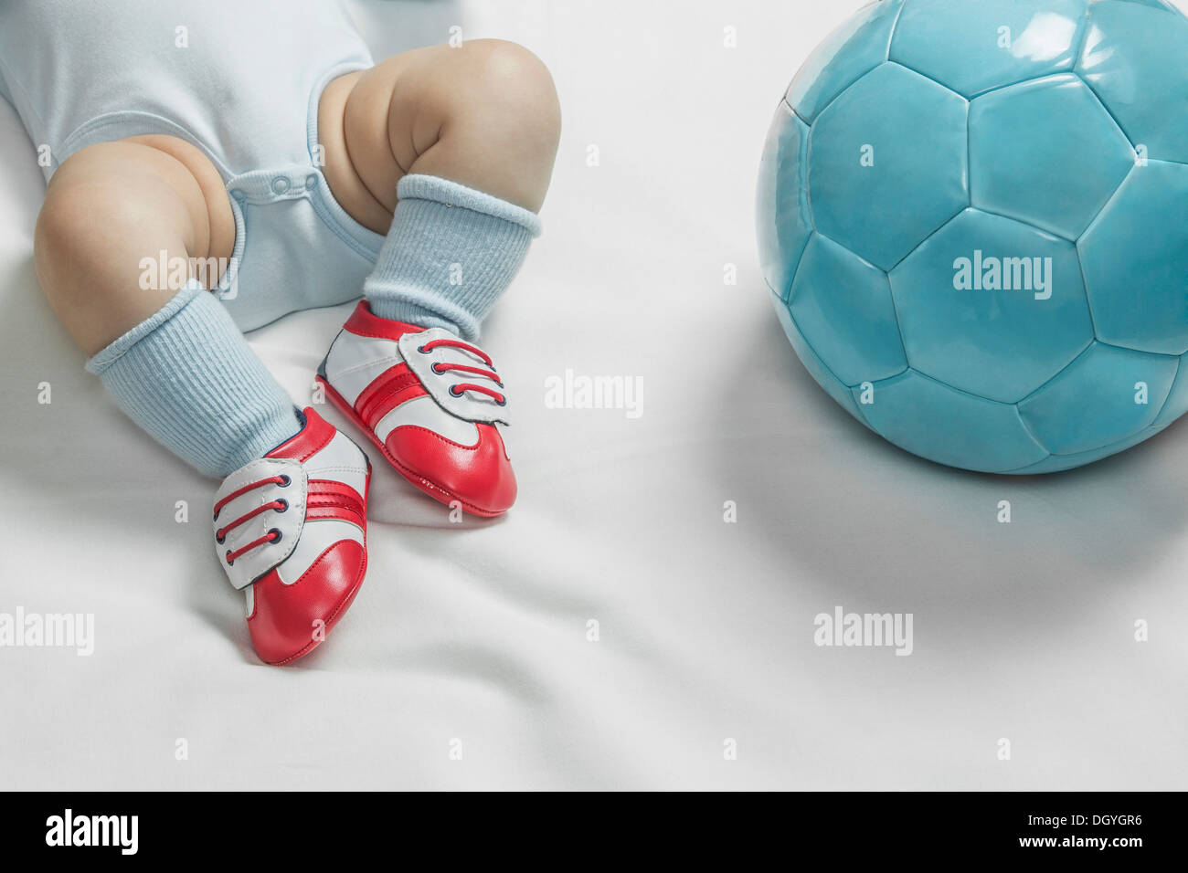 Un petit garçon portant des chaussures de foot bébé couché à côté d'un  ballon de foot Photo Stock - Alamy