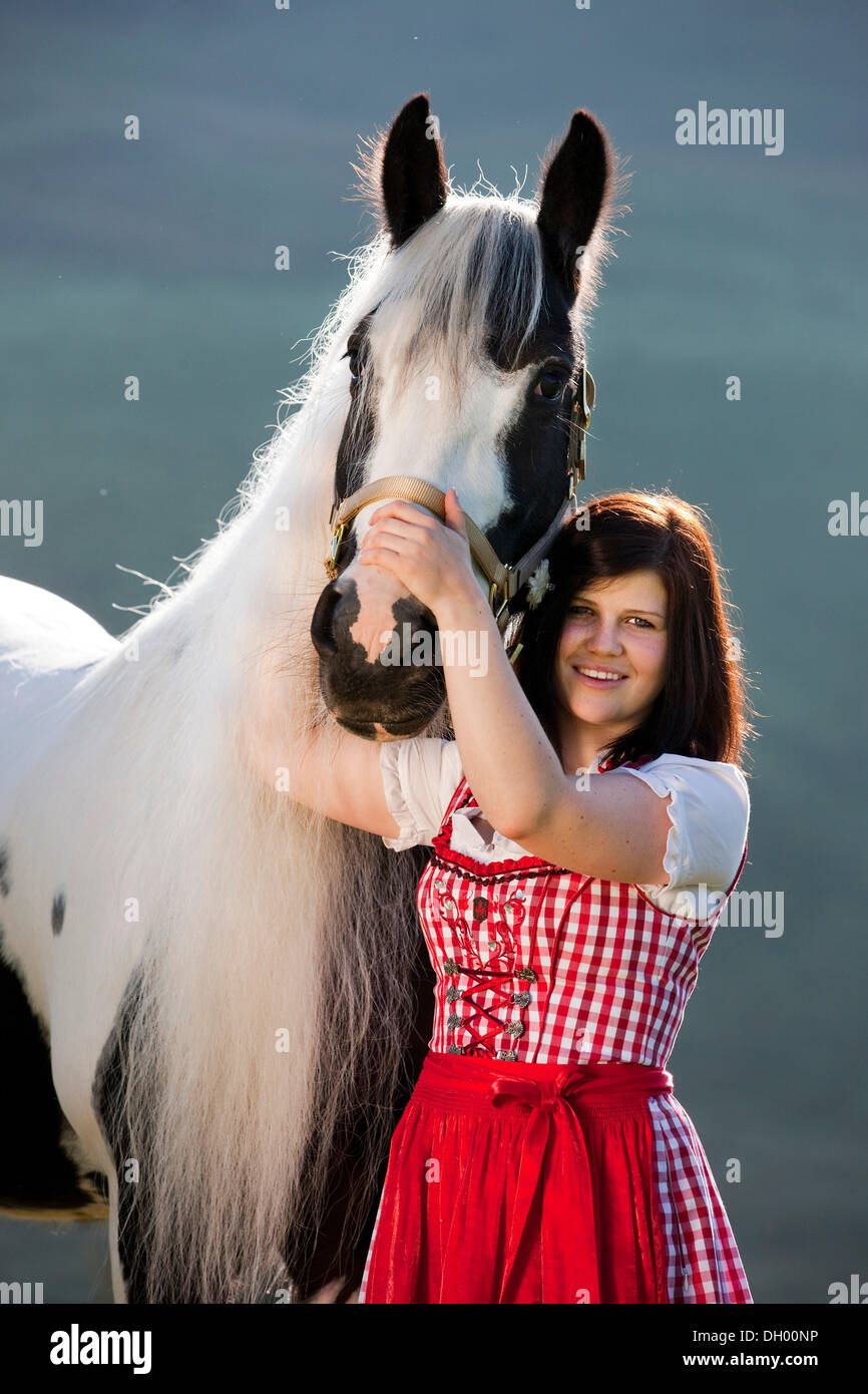 Jeune femme portant un dirndl de câlins avec un Gypsy Vanner ou cheval Tinker, Pinto, noir et blanc, Tyrol du Nord, l'Autriche, Europe Banque D'Images