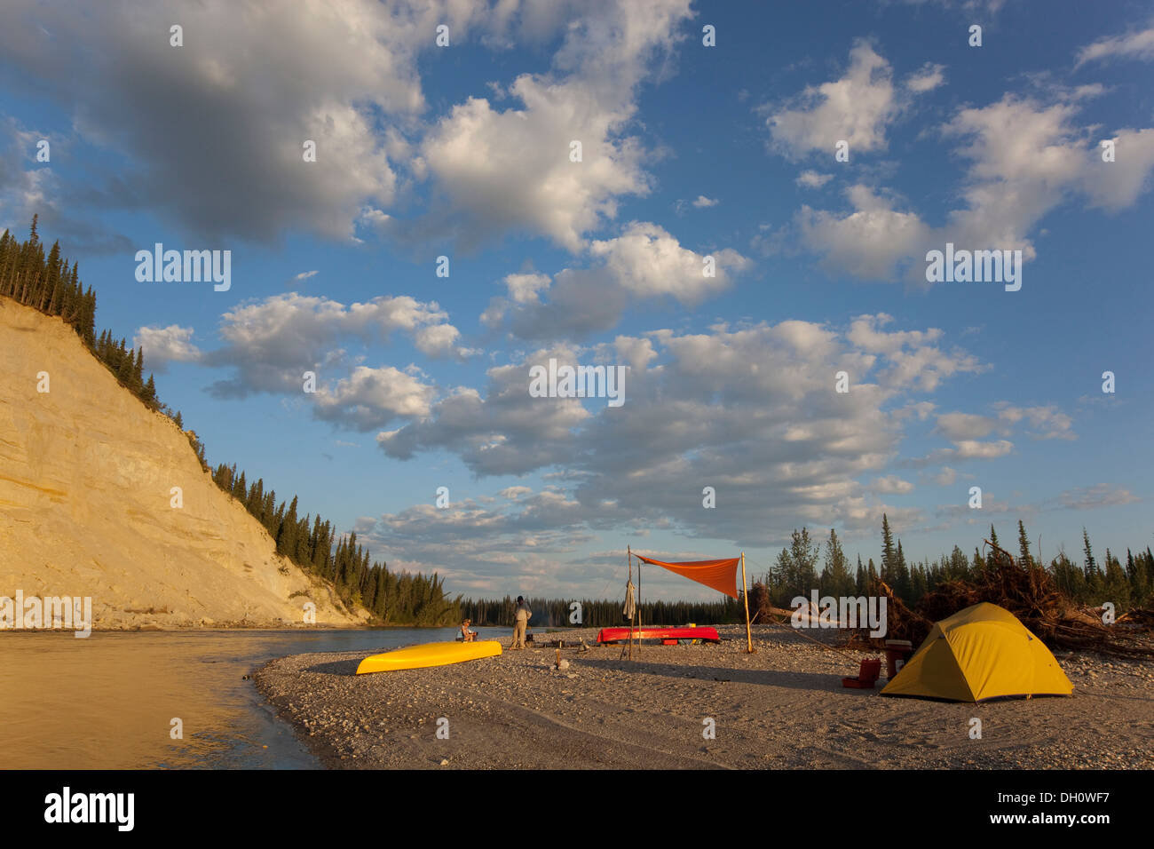 Camp avec tente et toile sur un banc de gravier, high cut bank derrière, Upper Liard River, Yukon Territory, Canada Banque D'Images