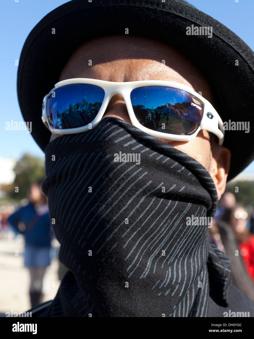 L'homme se cachant le visage avec masque de bandana, lunettes de soleil,  chapeau, et en marche de protestation Photo Stock - Alamy