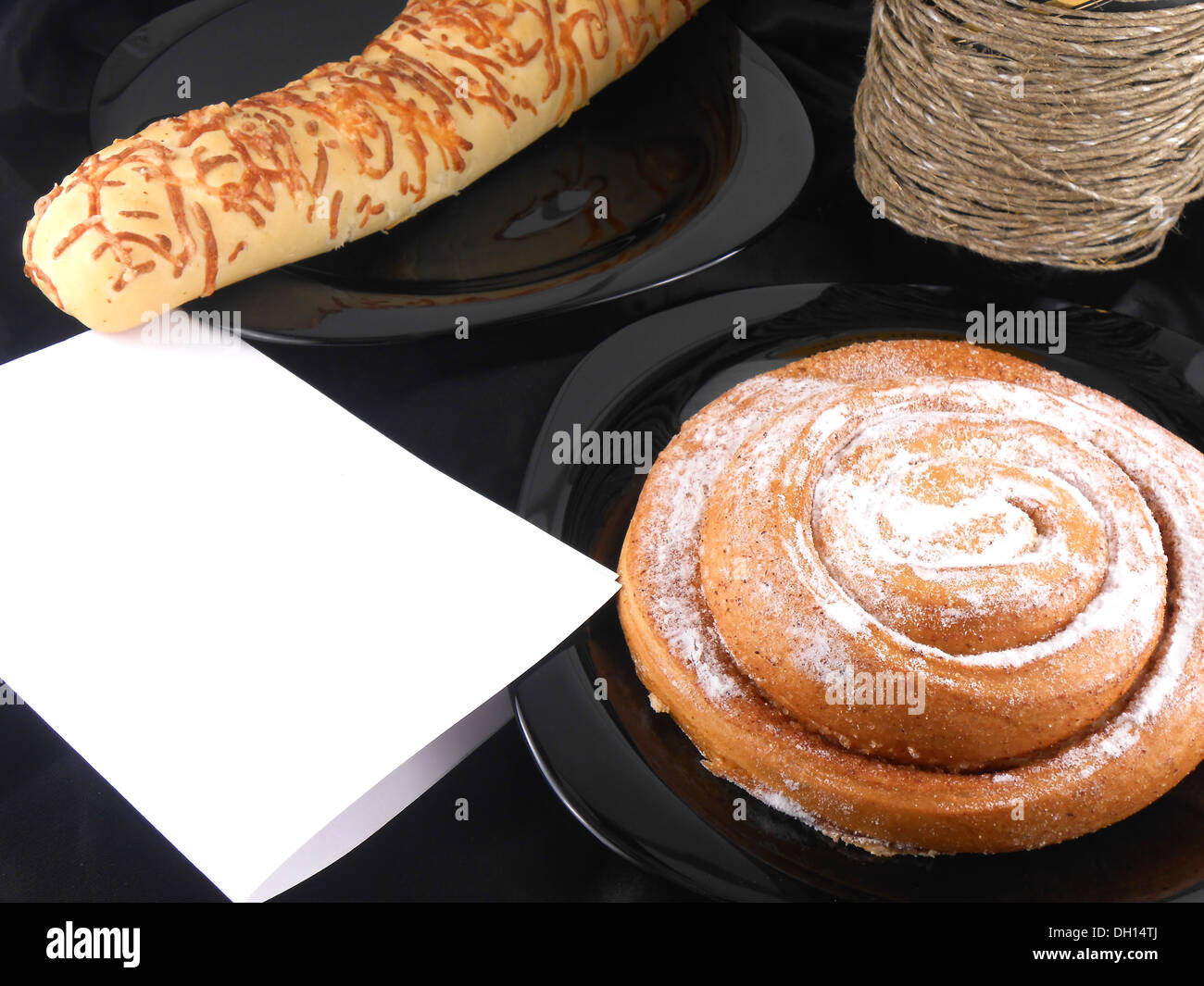 Gâteau sucré sur fond noir, papier blanc et bouteille de vin Banque D'Images