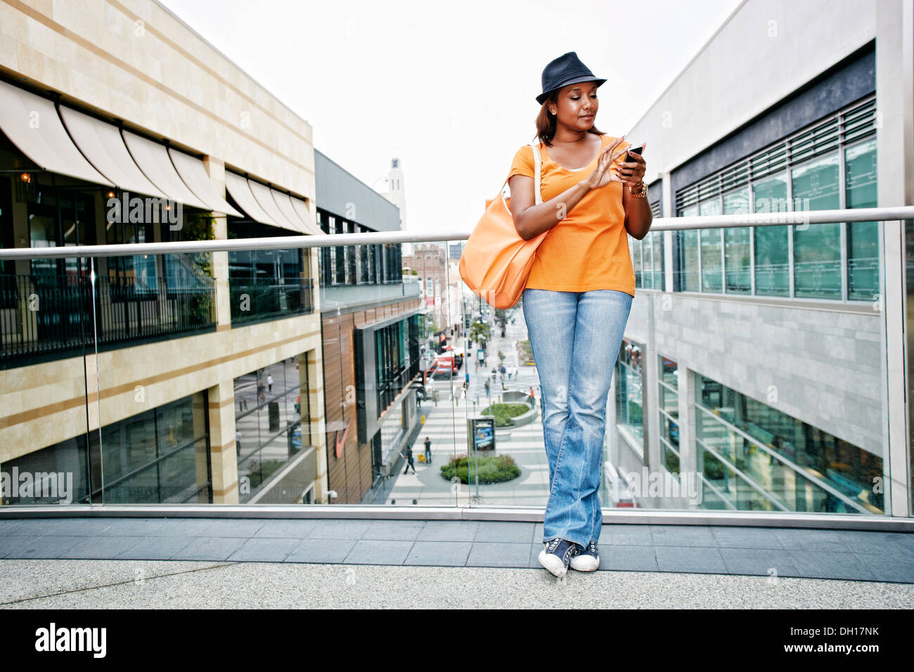 Black woman using cell phone on sky bridge au centre commercial Banque D'Images