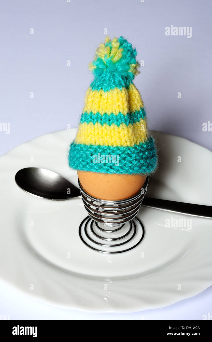 Oeuf dur dans un coquetier en métal surmonté d'un oeuf en tricot confortable. Banque D'Images