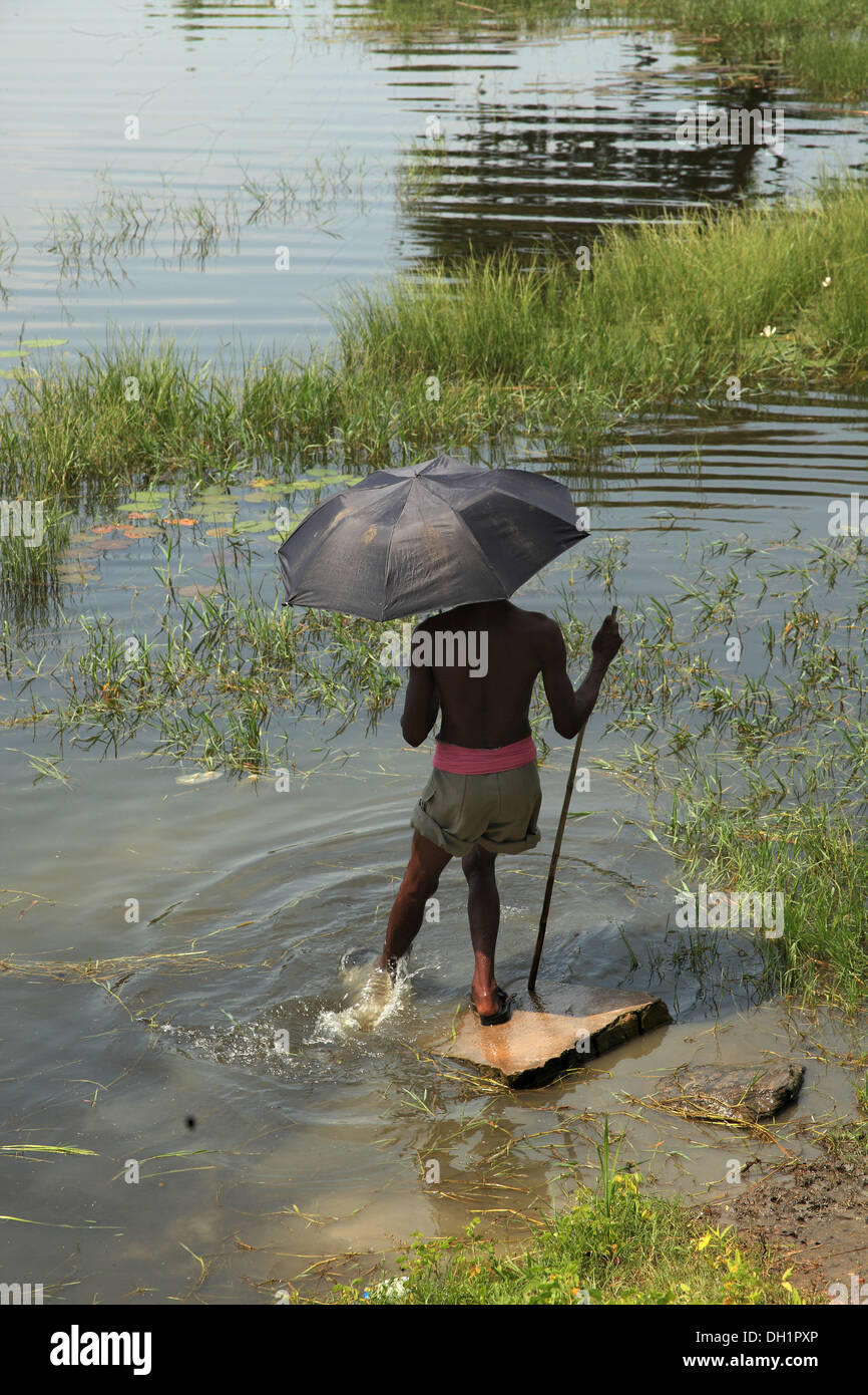 Parapluie noir garçon stick river Sambalpur Orissa en Inde Banque D'Images