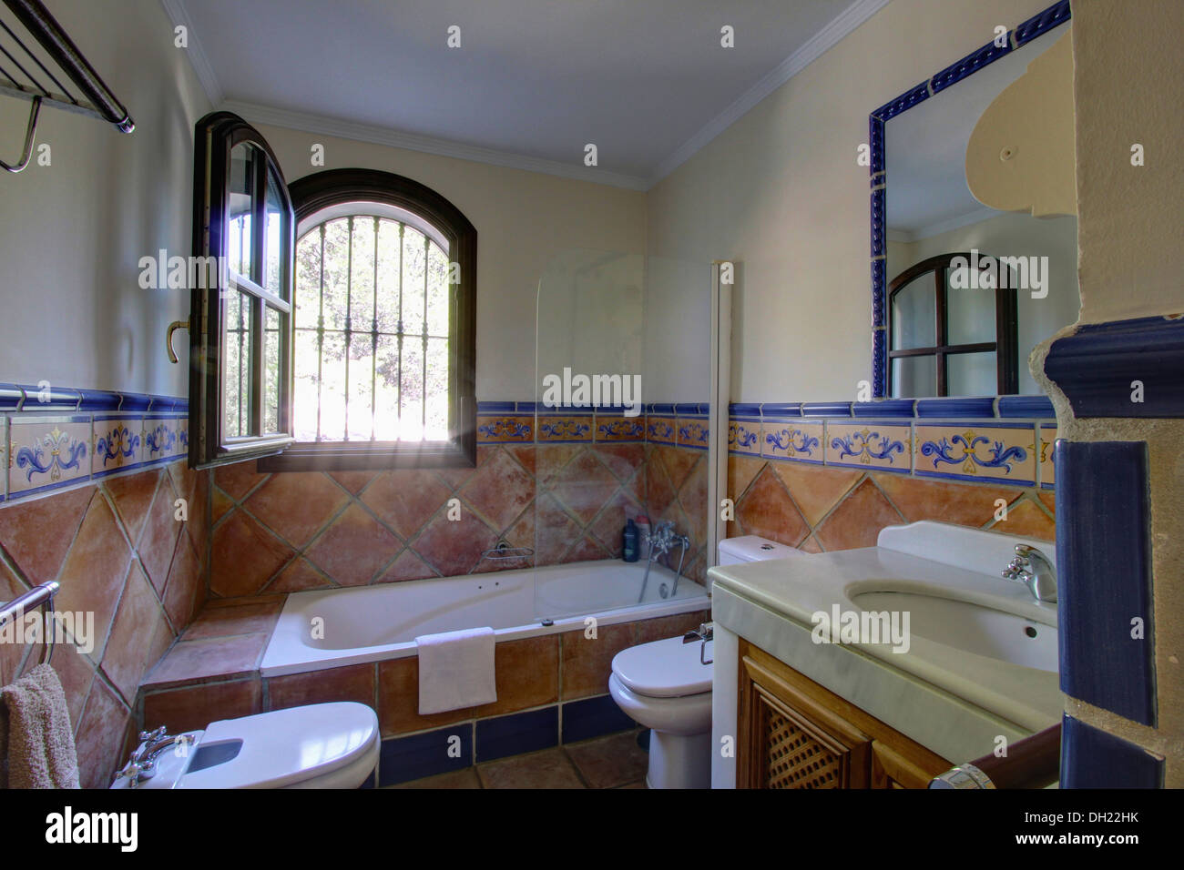 Fenêtre ouverte au-dessus de baignoire en espagnol salle de bains, sol en  terre cuite mur à hauteur de dado Photo Stock - Alamy