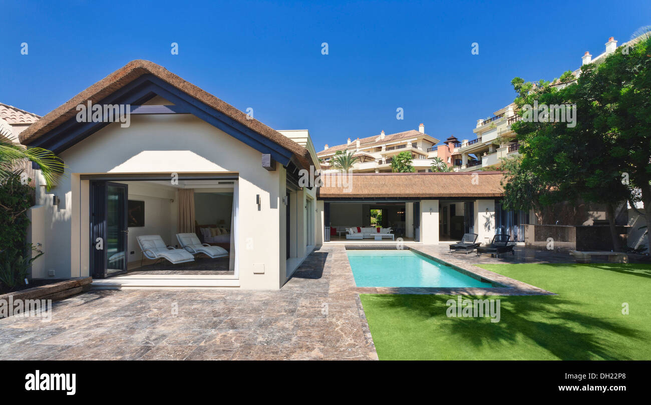 Portes pliantes sur extension salon à côté de la piscine turquoise dans jardin clos de nouvelle construction villa en espagnol Banque D'Images