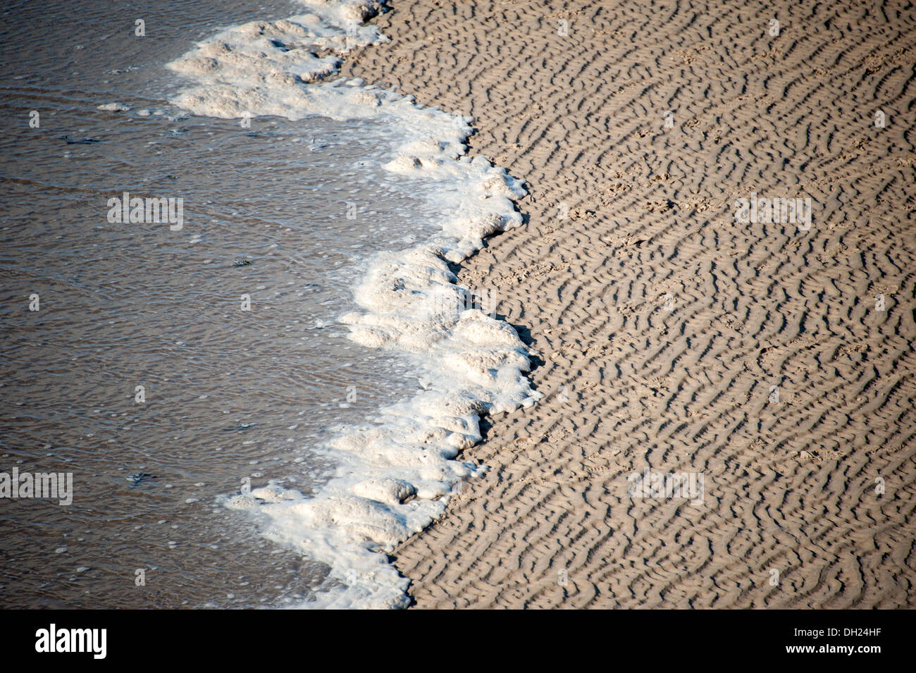 Écume de mousse à bord des eaux de marée plage Banque D'Images