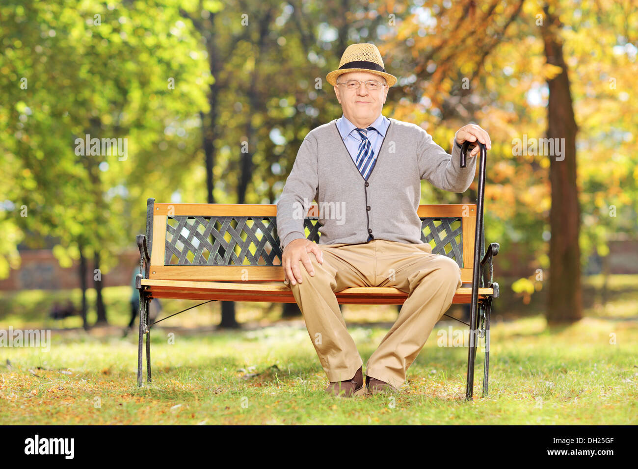 La haute atmosphère gentleman assis sur un banc et looking at camera in a park Banque D'Images