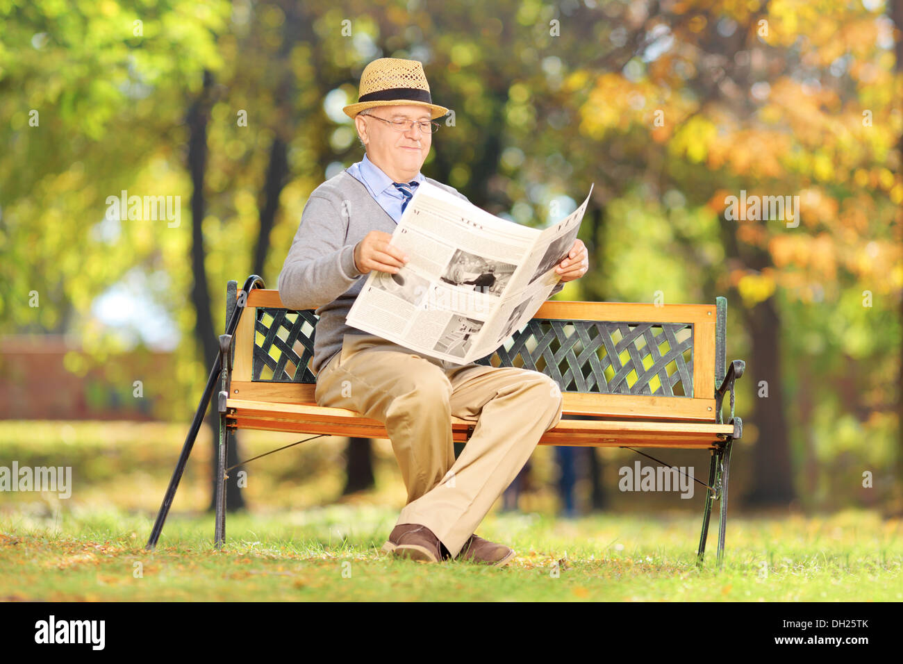 Représentant Senior assis sur un banc de lire le journal dans un parc Banque D'Images