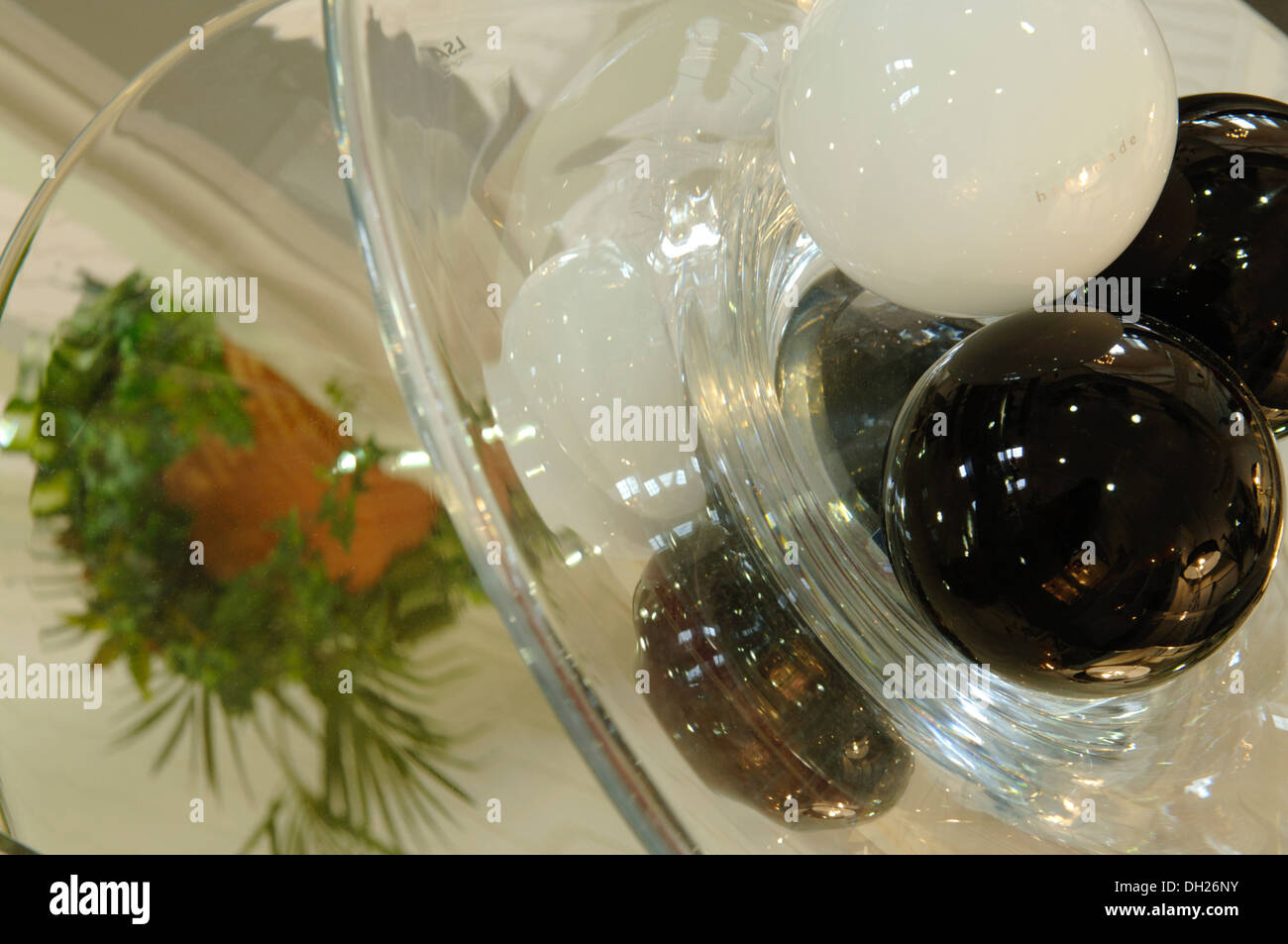 Globes en verre décoratif placé sur une table en miroir reflétant une plante Banque D'Images