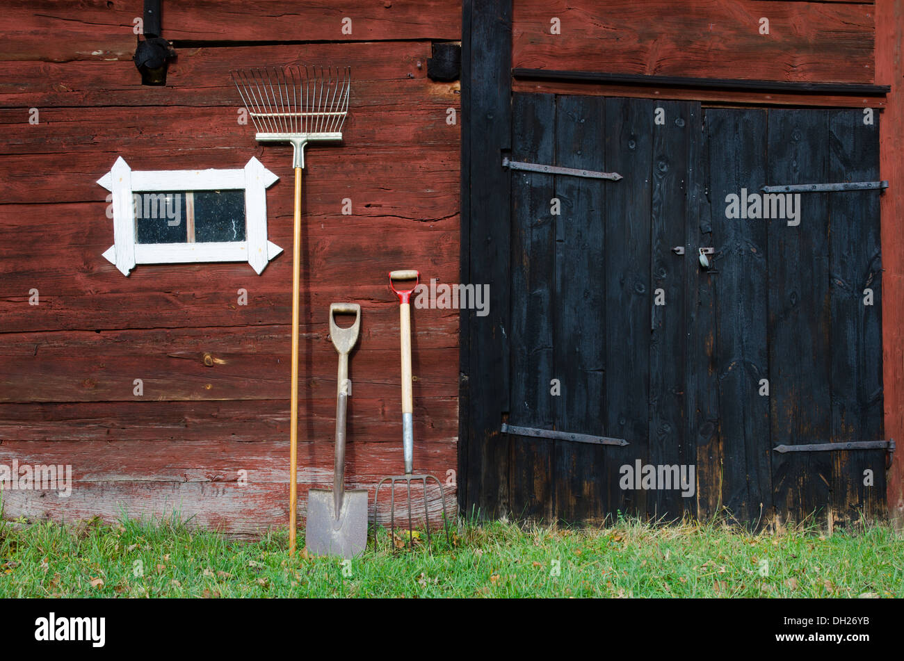 Outils de jardin dans un vieux mur de la grange. Banque D'Images