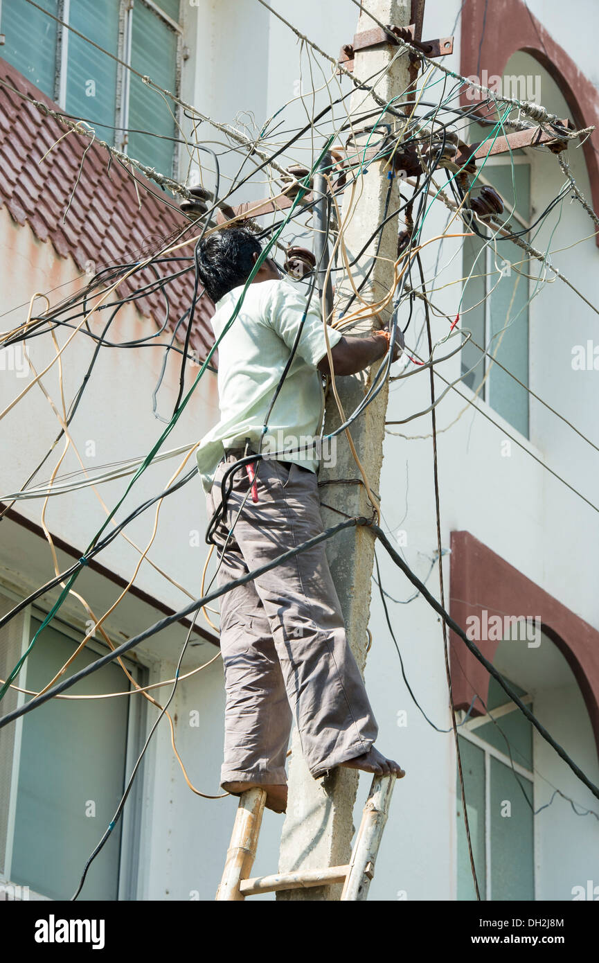 Electrician indiennes d'un pylône d'électricité dans les rues de Puttaparthi, Andhra Pradesh, Inde Banque D'Images