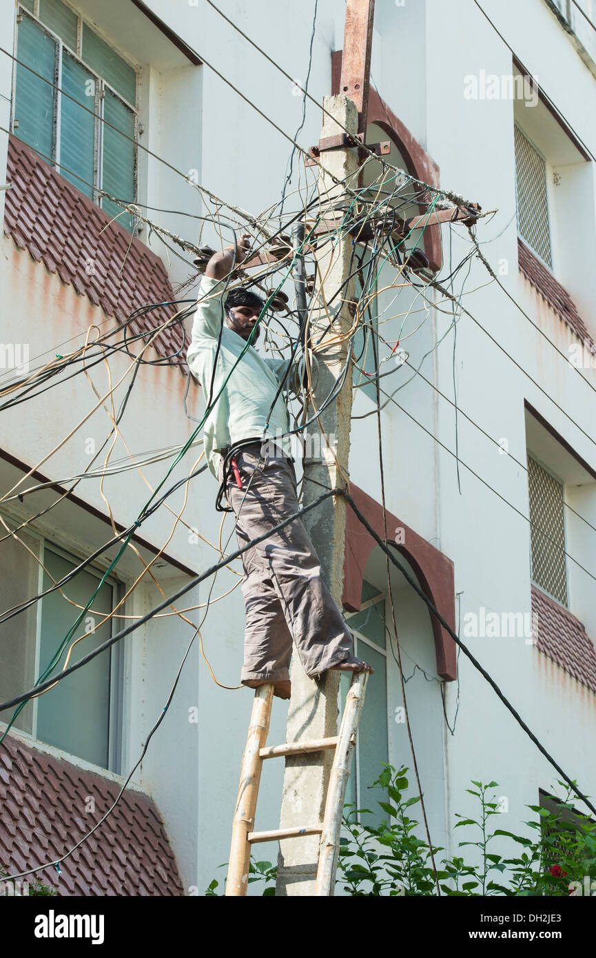 Electrician indiennes d'un pylône d'électricité dans les rues de Puttaparthi, Andhra Pradesh, Inde Banque D'Images