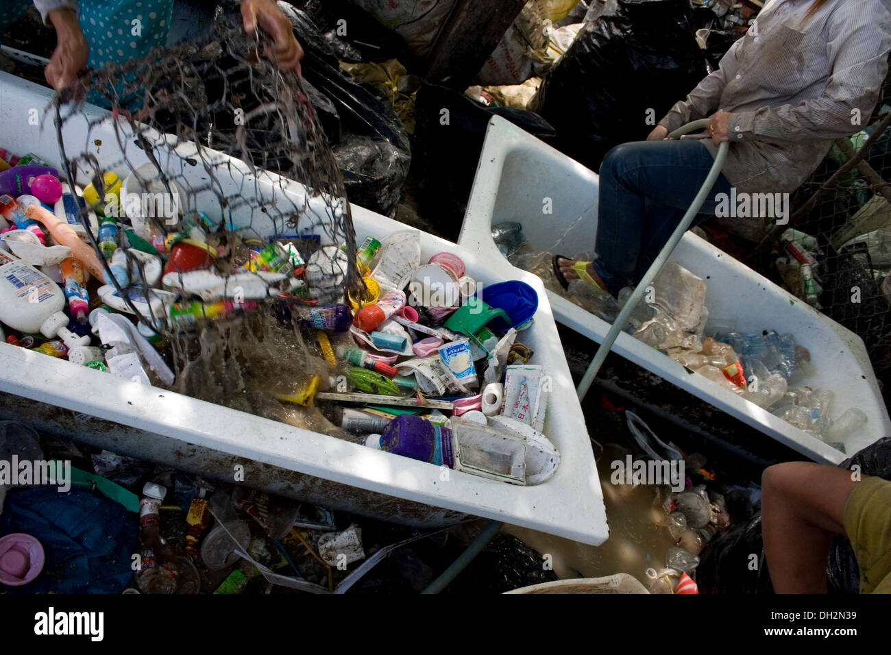 Les gens sont recyclables de rinçage dans une baignoire ancienne près d'un grand dépotoir à Phnom Penh, Cambodge. Banque D'Images