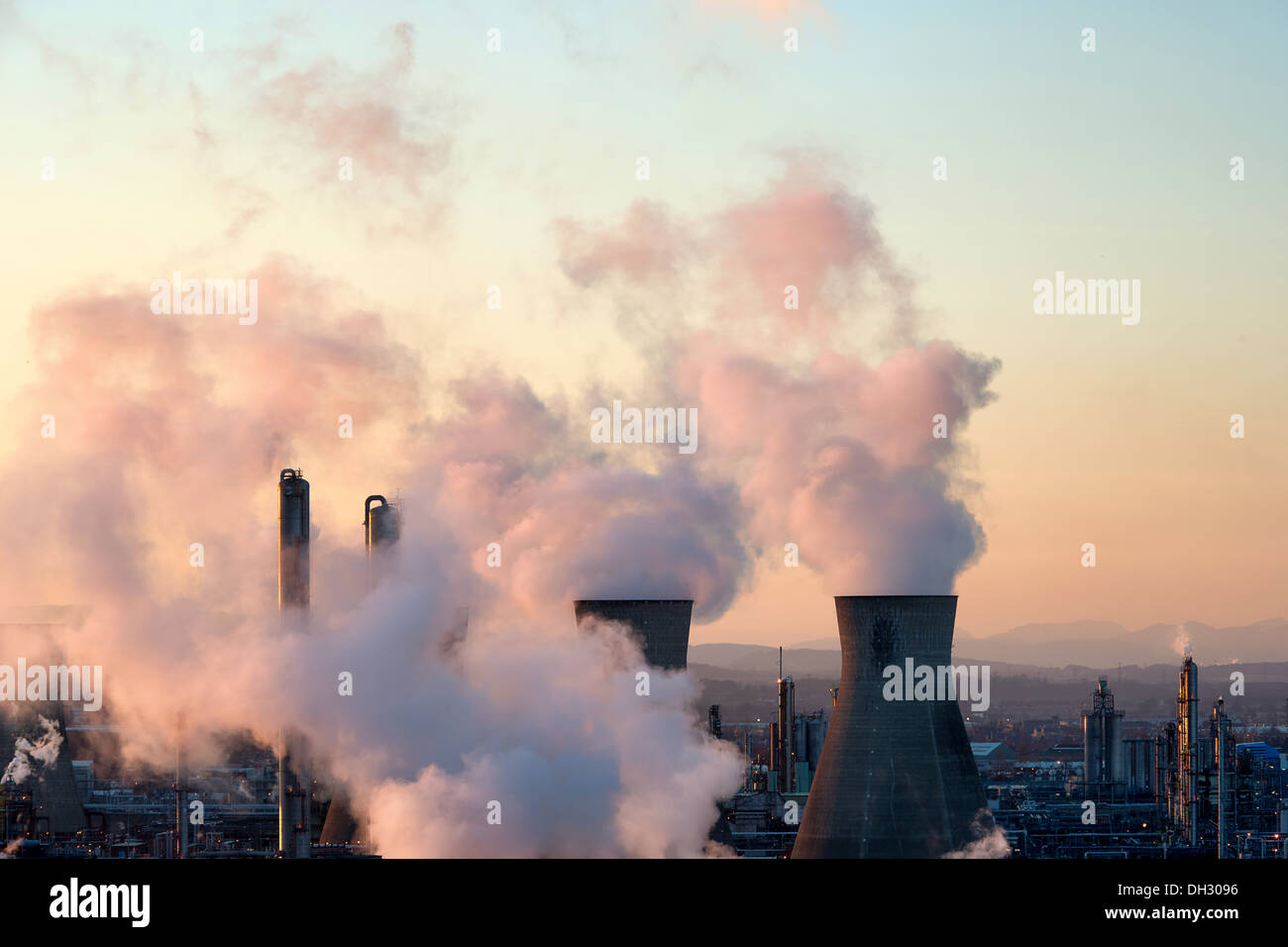 Les cheminées de la raffinerie de pétrole de Grangemouth crachant de la fumée dans l'atmosphère, la coloration rose de vapeurs au coucher du soleil Banque D'Images