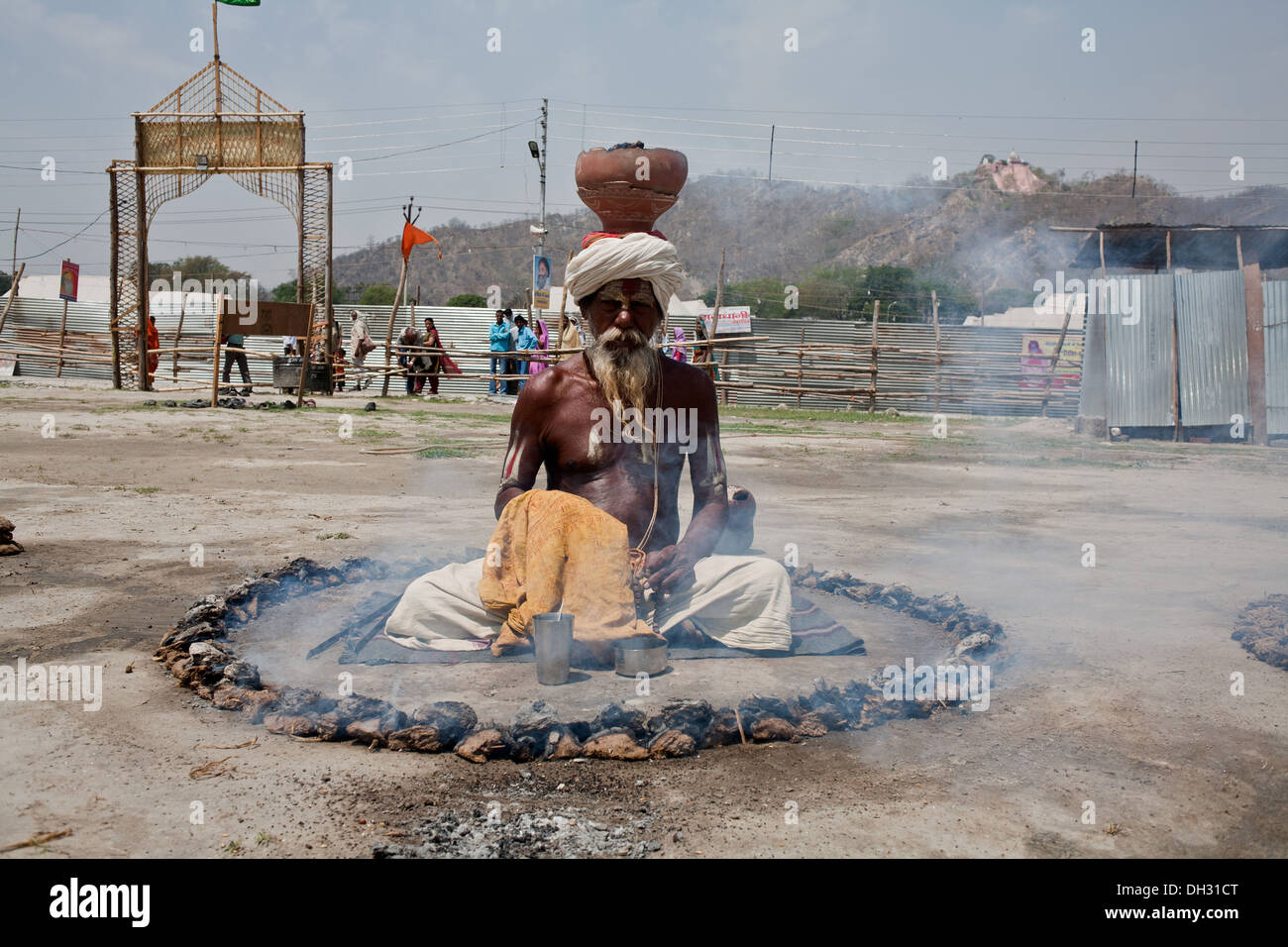 Sadhu priant entouré par la combustion du charbon et de l'équilibrage sur pot de combustion Kumbh tête Uttarakhand Haridwar équitable Inde Asie Banque D'Images