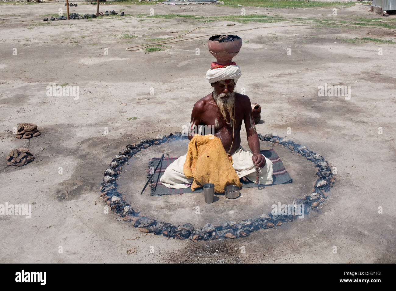 Sadhu faire pénitence pooja entouré par la combustion du charbon et de l'équilibrage de brûler du charbon pot sur la tête juste Uttarakhand Haridwar Kumbh Asie Inde Banque D'Images