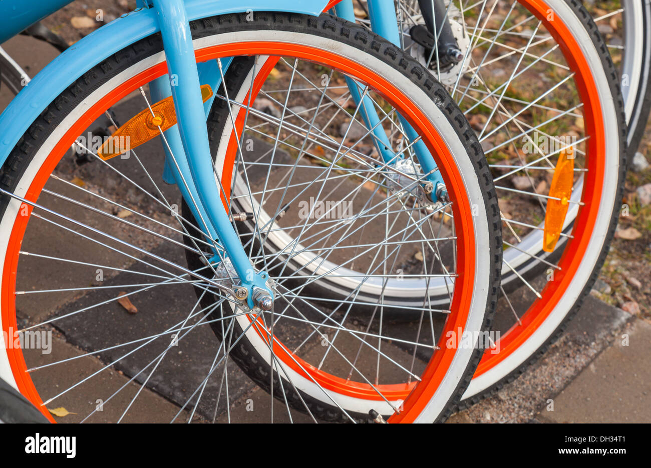 La location des vélos colorés se tenir dans une rangée sur un parking gratuit Banque D'Images
