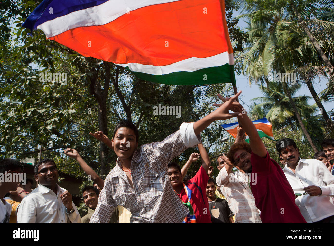 Hommes partisans dansant agitant le drapeau du parti politique MNS célébrant la victoire du candidat Mumbai Maharashtra Inde Asie élections indiennes Banque D'Images