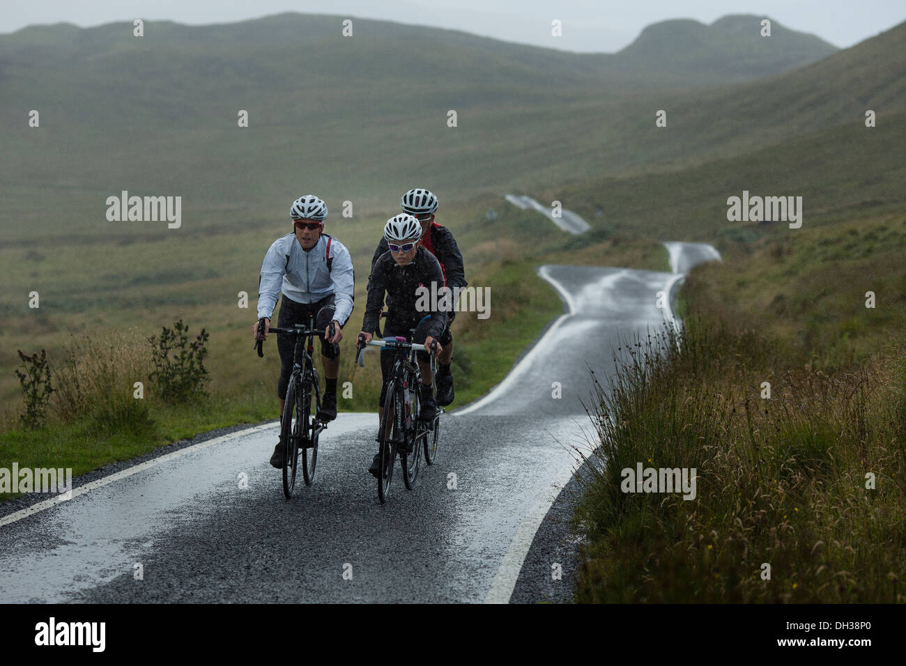 Trois cyclistes roulent un chemin humide dans les Highlands, Ecosse, Royaume-Uni Banque D'Images