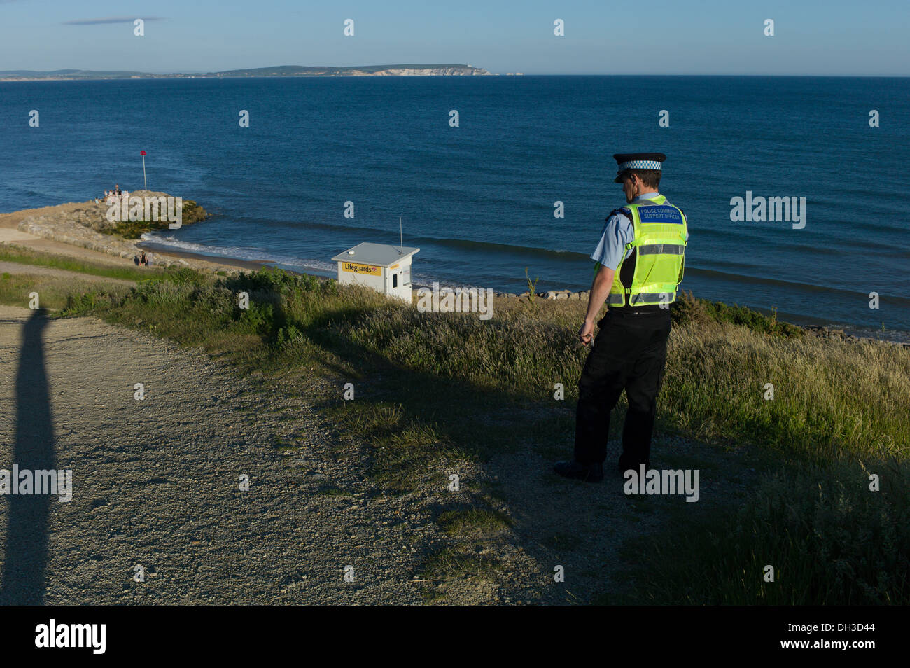 Un agent de soutien de la police communautaire donne sur la mer sur la plage de highcliffe et l'île de Wight et aiguilles Banque D'Images