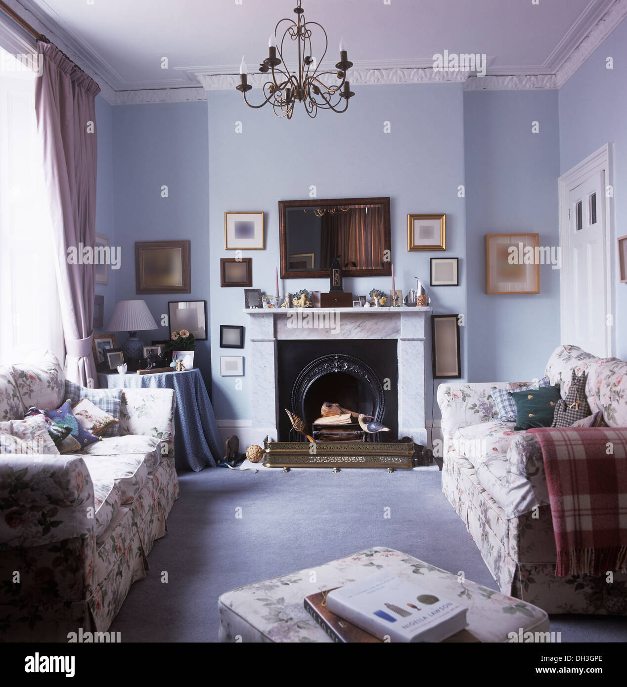 Canapés de fleurs de chaque côté de la cheminée de marbre dans les petites, bleu pâle, salon avec tapis bleu pâle lustre métallique Banque D'Images