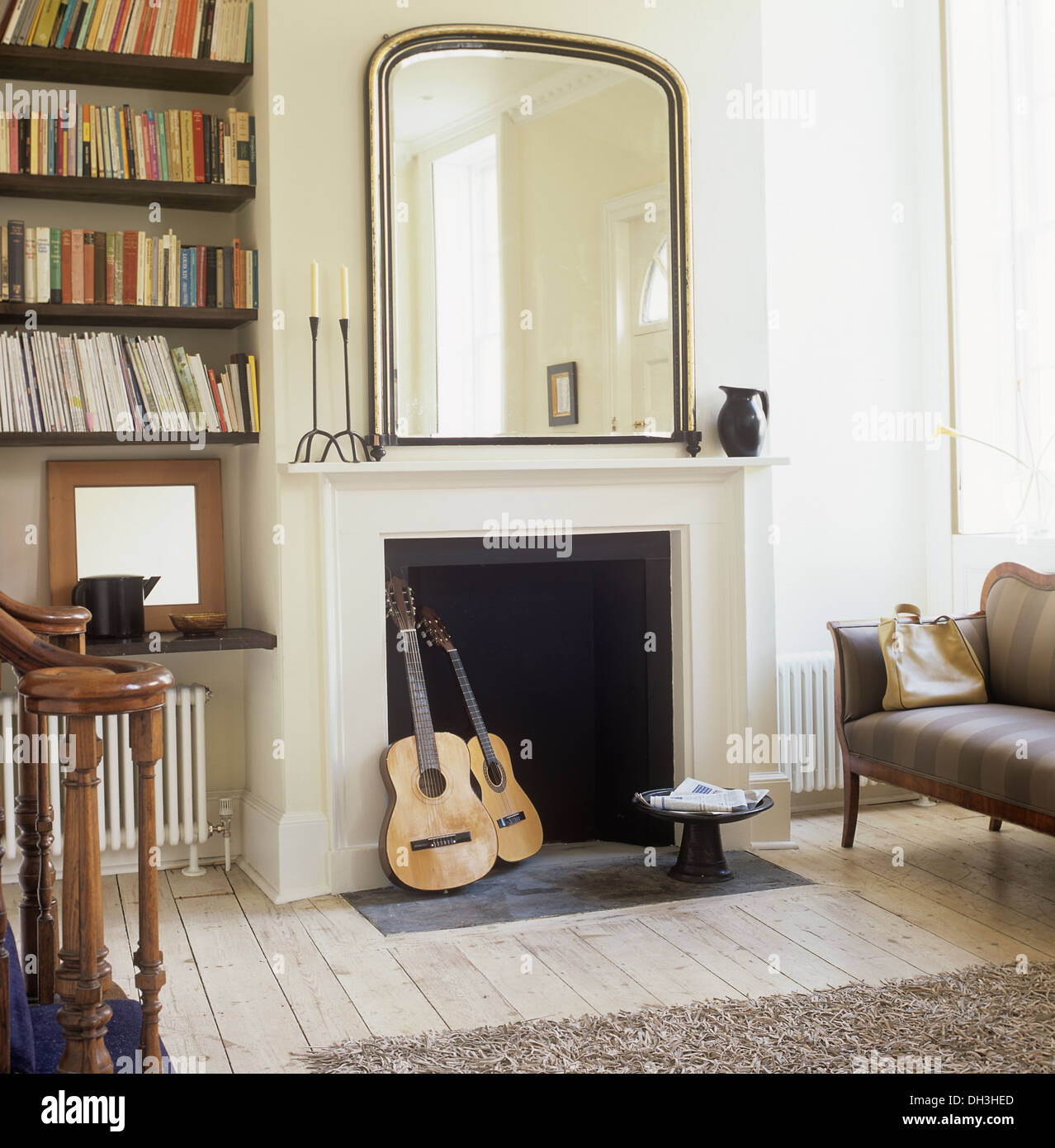 Guitares dans une cheminée ci-dessous Grand miroir mural dans le hall salon  avec bibliothèque et un canapé gris Photo Stock - Alamy