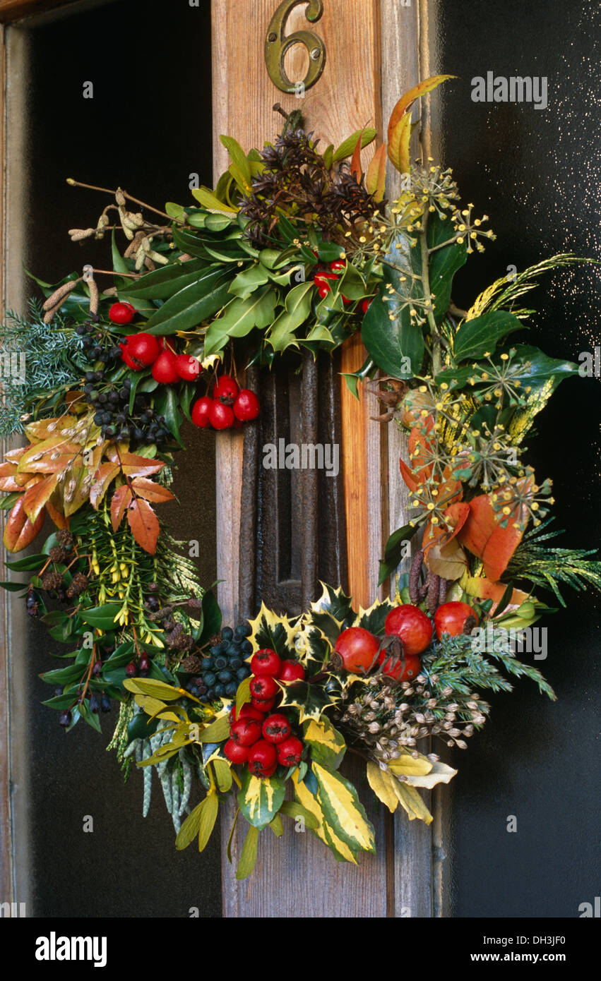 Close-up de porte avec couronne de Noël sur porte faite de feuillage d'hiver et rouge des baies de houx Banque D'Images