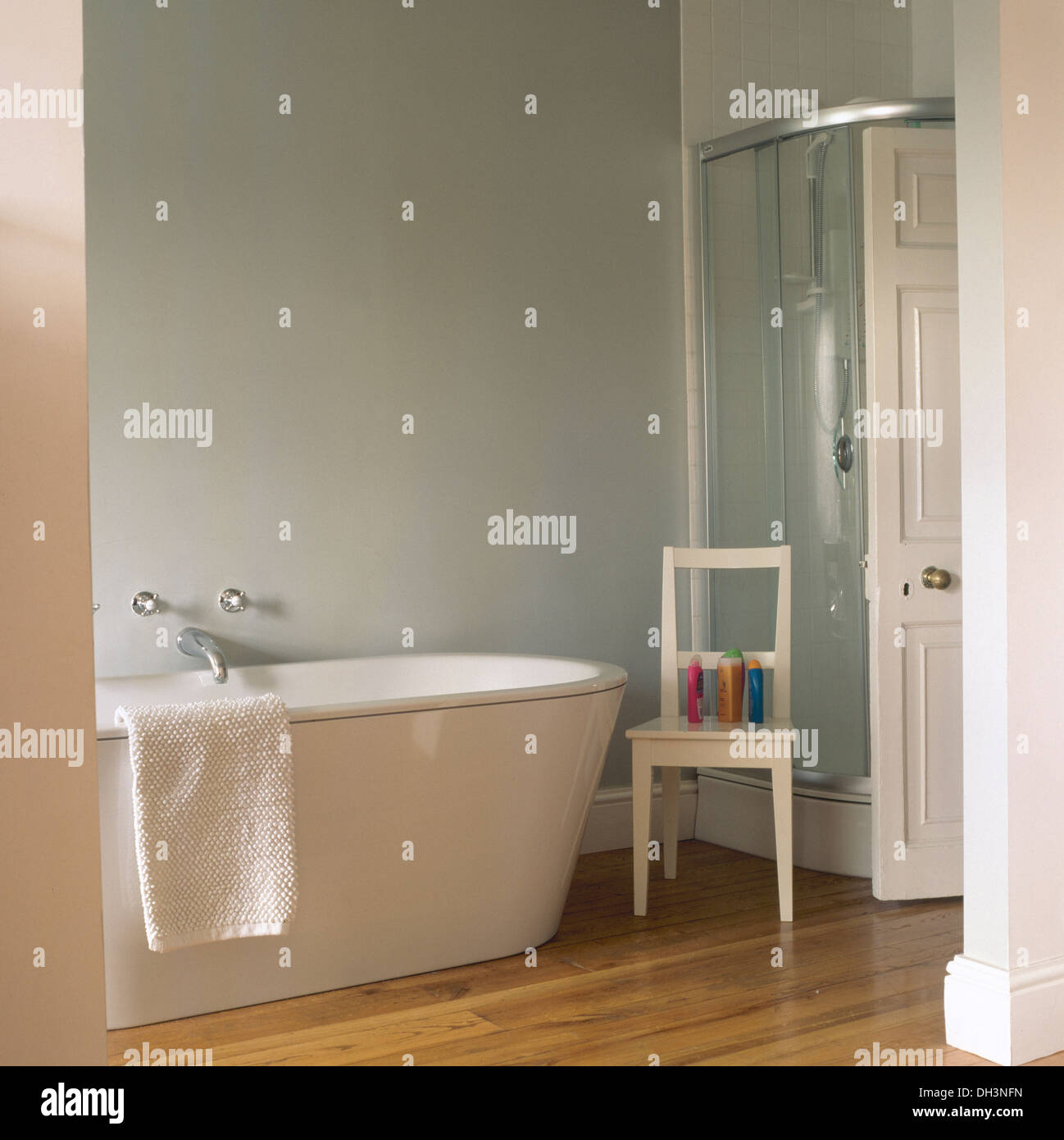 Chaise en bois blanc à côté de baignoire sur pieds en gris pâle, moderne  salle de bains avec douche en verre et le parquet du cabinet Photo Stock -  Alamy