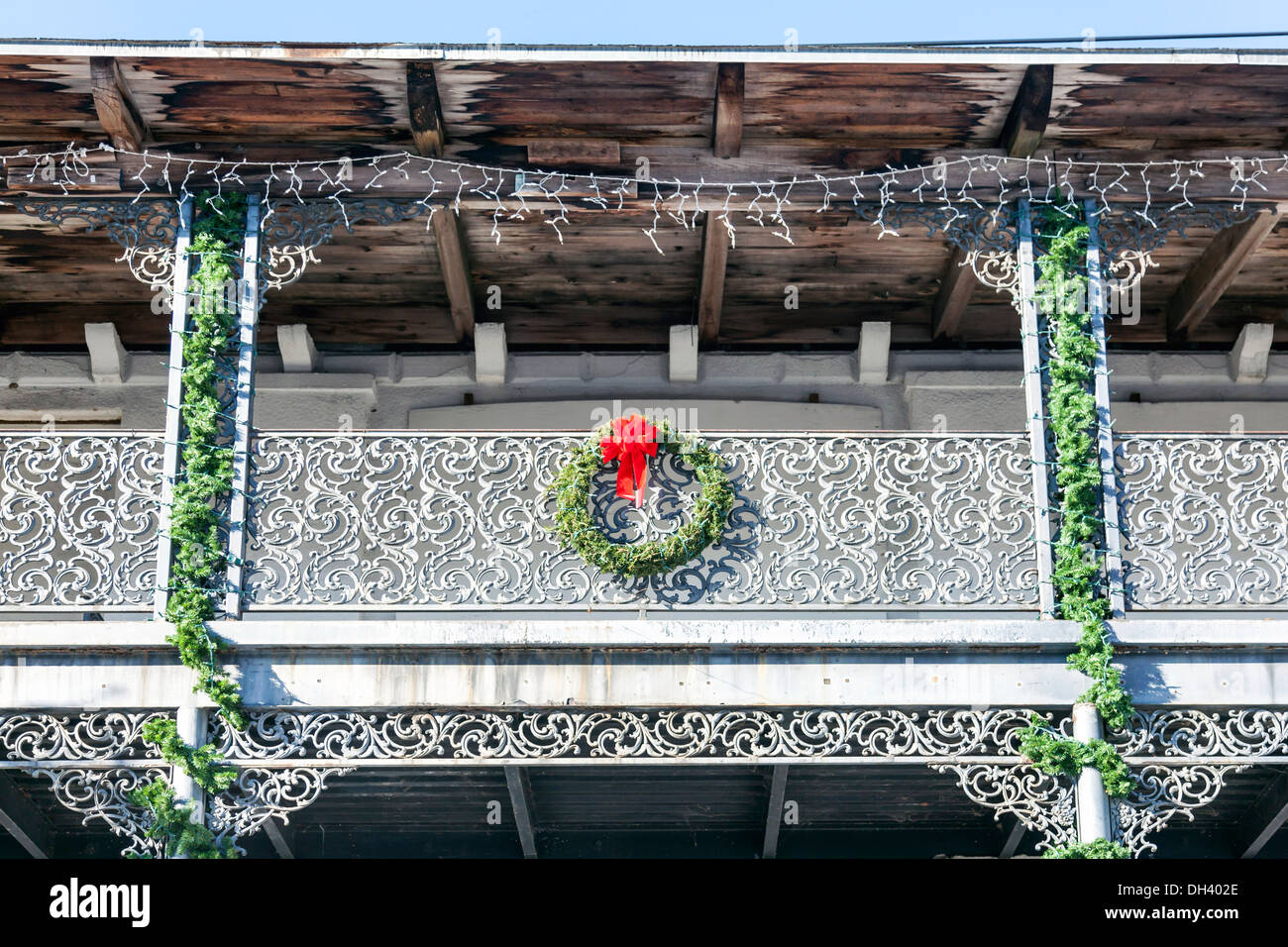 Ancienne balustrade du balcon en fer forgé et guirlandes wreath with red bow.poutre en bois et toit de planches a structure de l'eau visible Banque D'Images