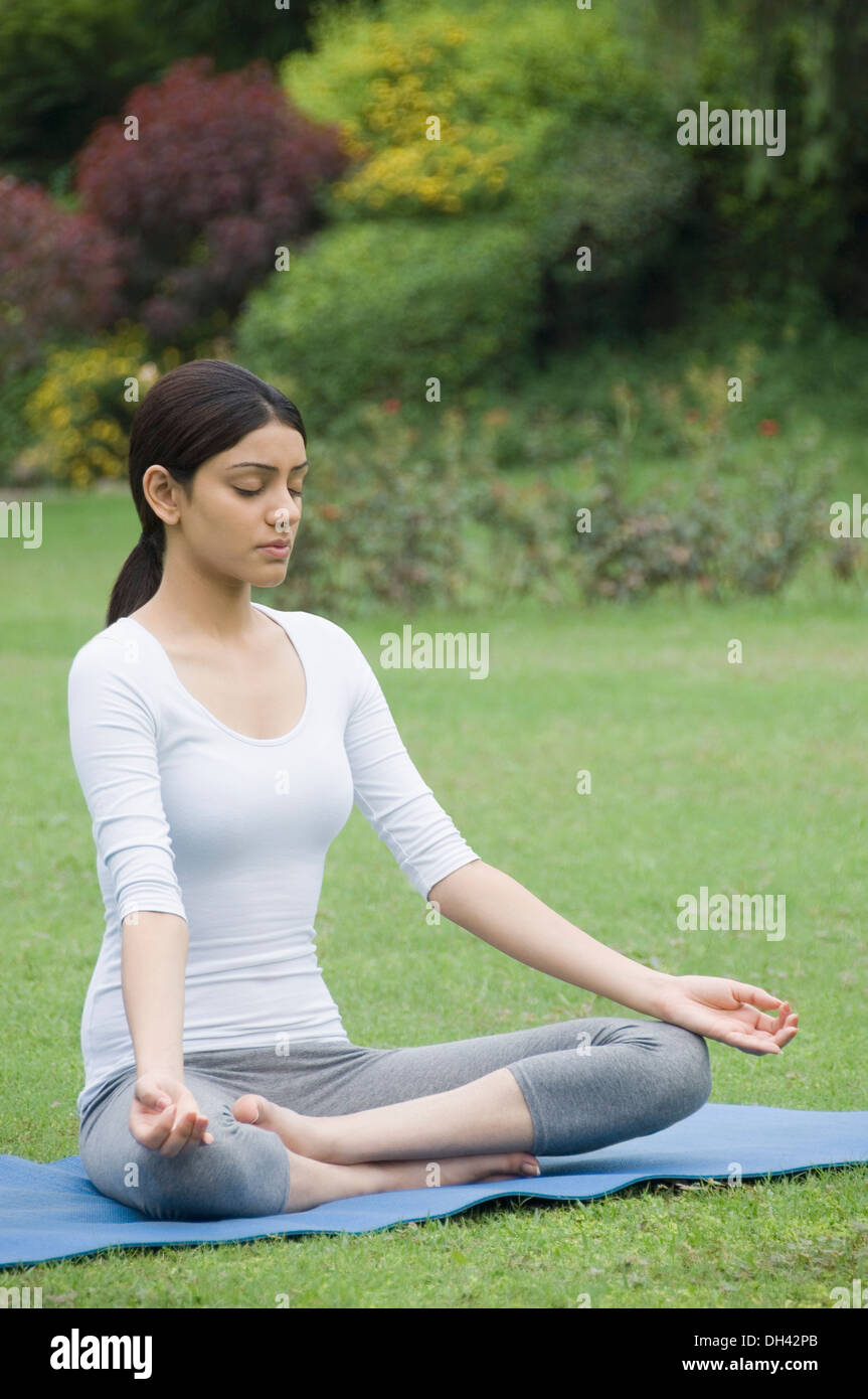 Woman practicing yoga in a park Banque D'Images