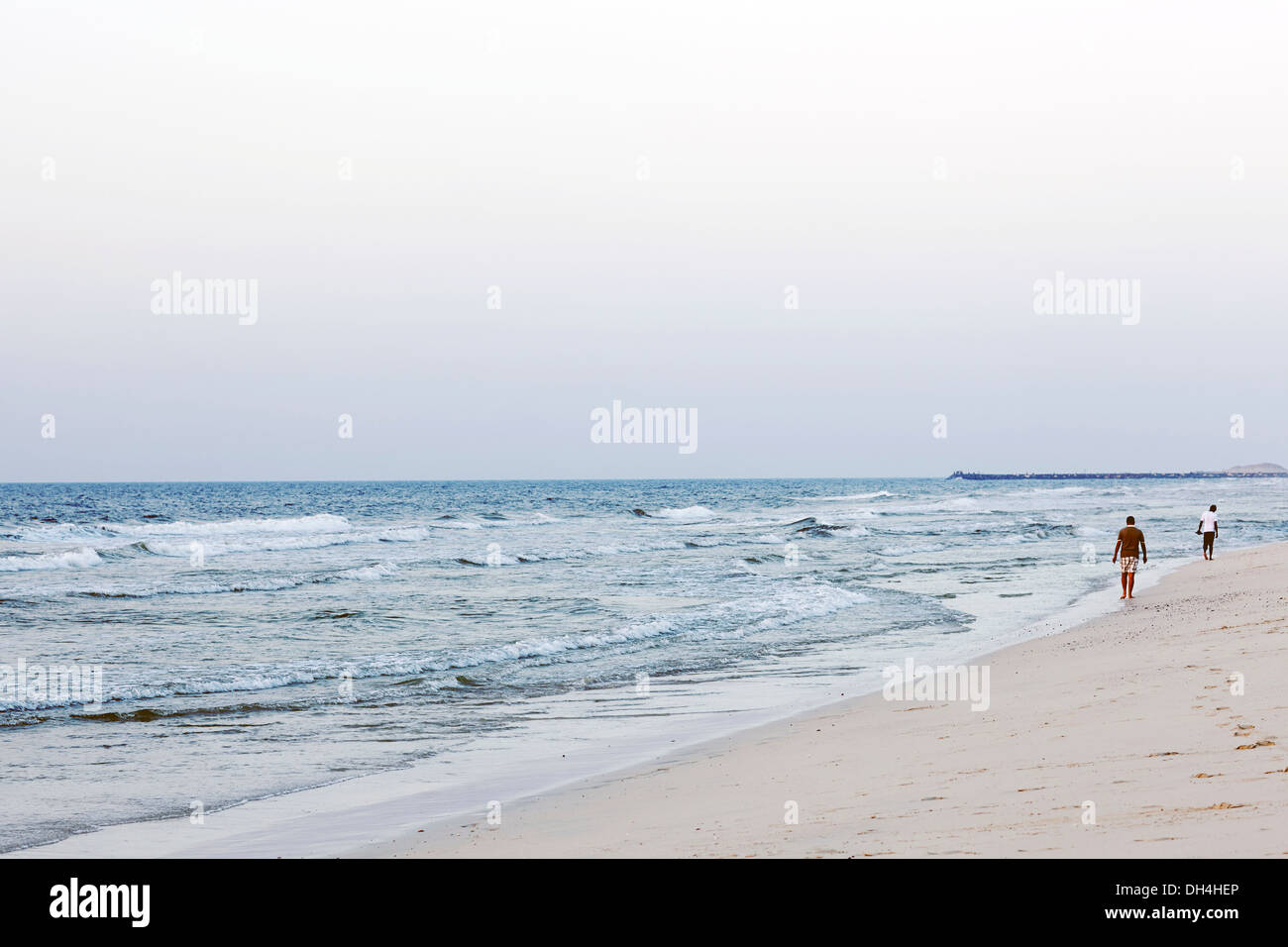 Deux garçons marche loin de la caméra le long de la plage pendant le matin Banque D'Images