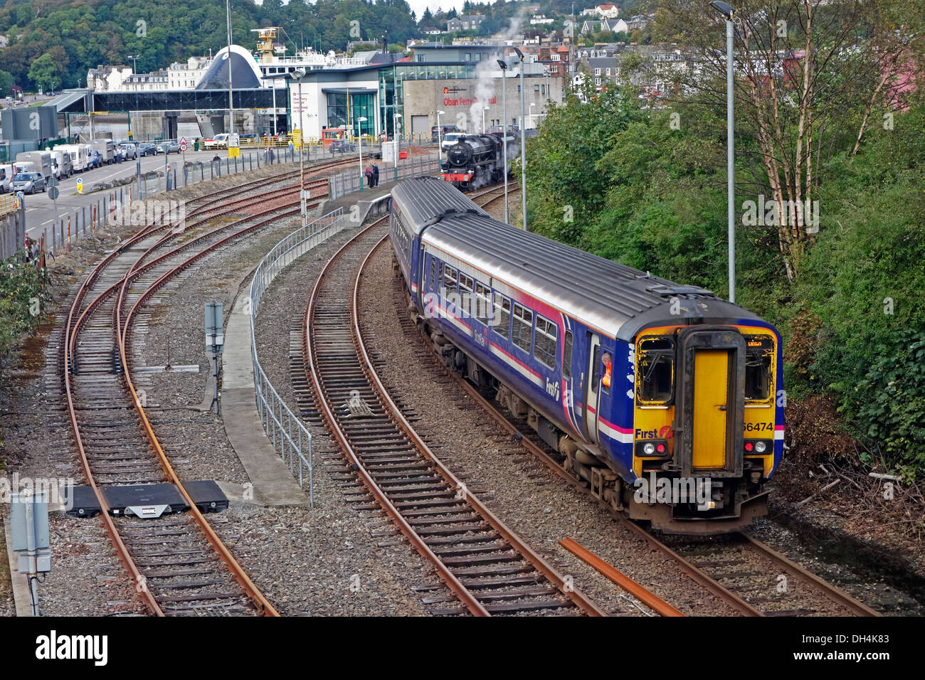 Première Classe Scotrail DMU 156 arrive à la gare en Ecosse Oban & machine à vapeur prête à partir avec train d'excursion Banque D'Images