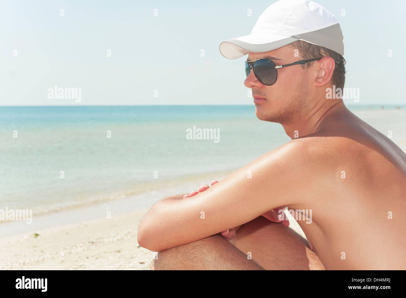 Guy dans le port lunettes noires sur une plage Banque D'Images