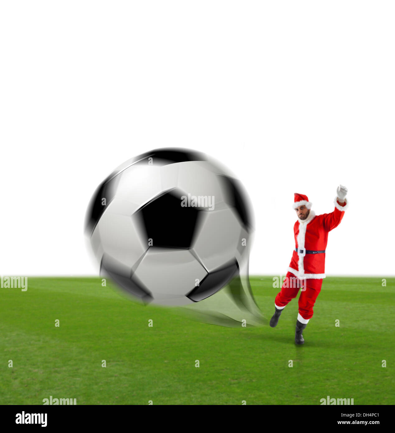 Santa Calus botter un ballon de soccer sur l'herbe et fond blanc Banque D'Images