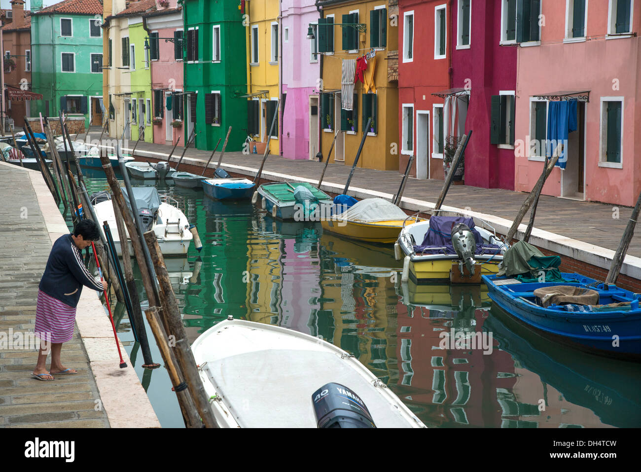 Nettoyage de la femme de la chaussée au bord du canal. Burano, lagune de Venise, Italie. Banque D'Images