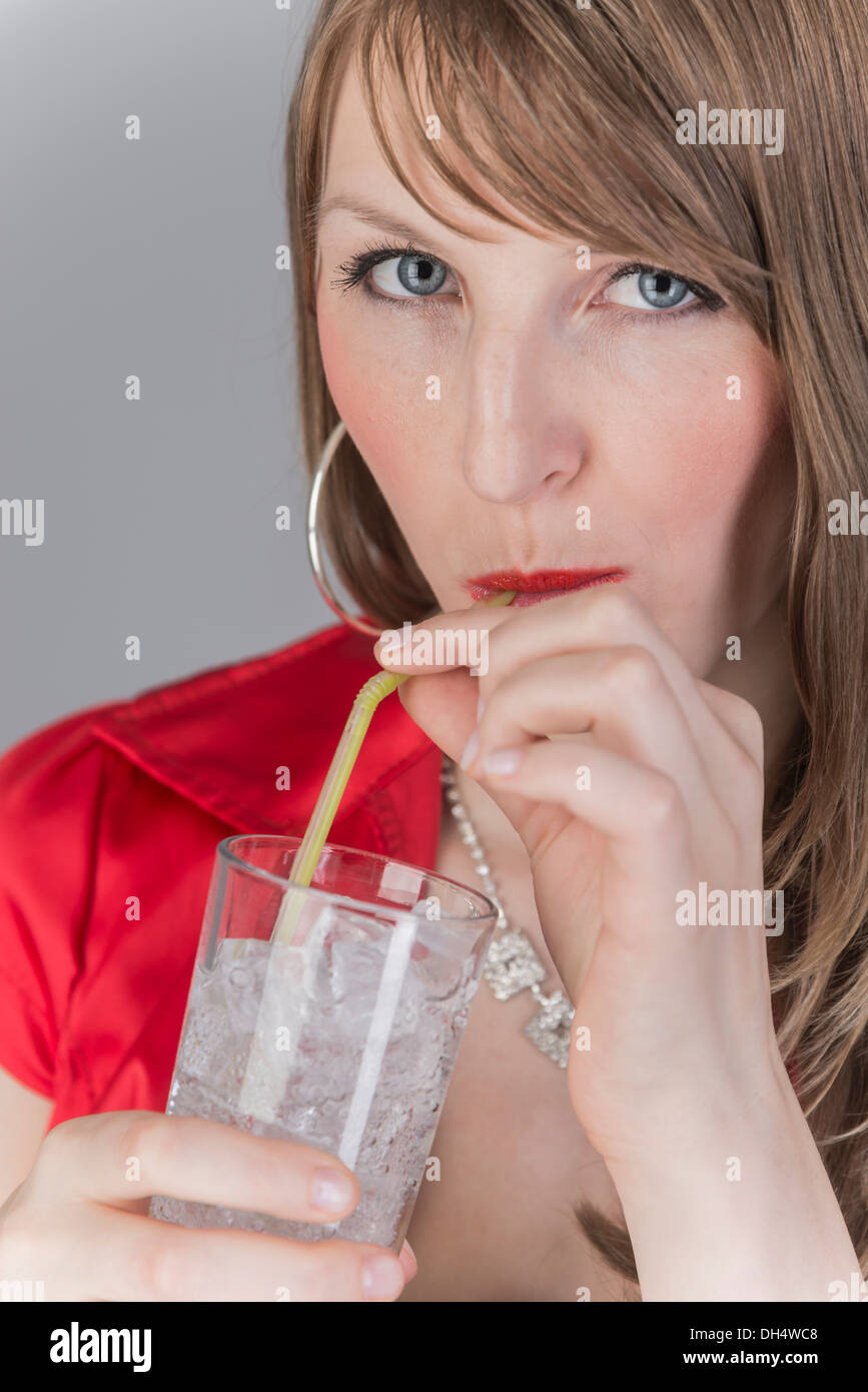 Glas avec des cubes de glace et liquide clair verre dans la main d'une jeune femme Banque D'Images